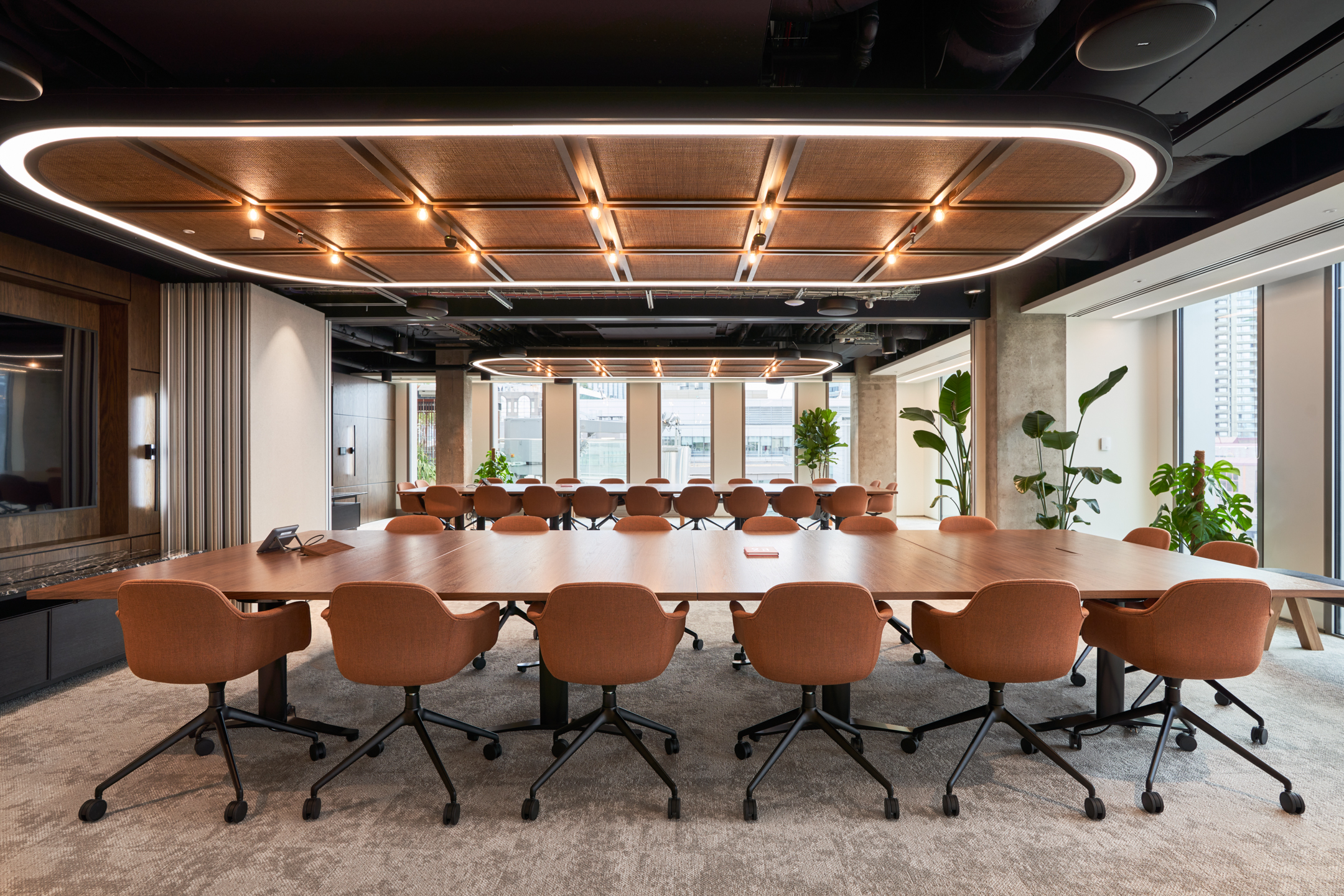 A modern boardroom with a large table and stylish lighting in the HYLO building. The office space is designed for strategic discussions and team collaboration.