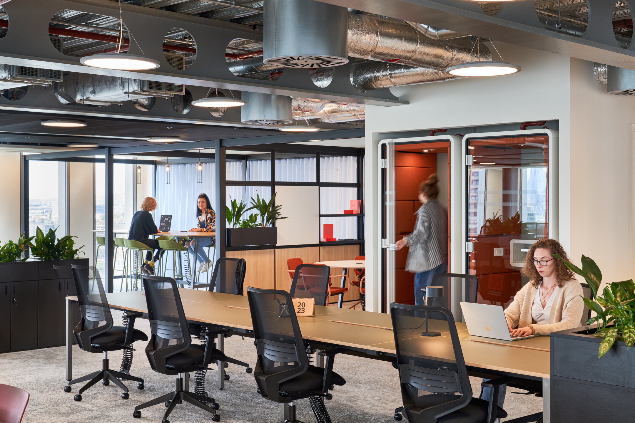 An open workspace with modern desks, break-out spaces and private phone booths in the HYLO building.