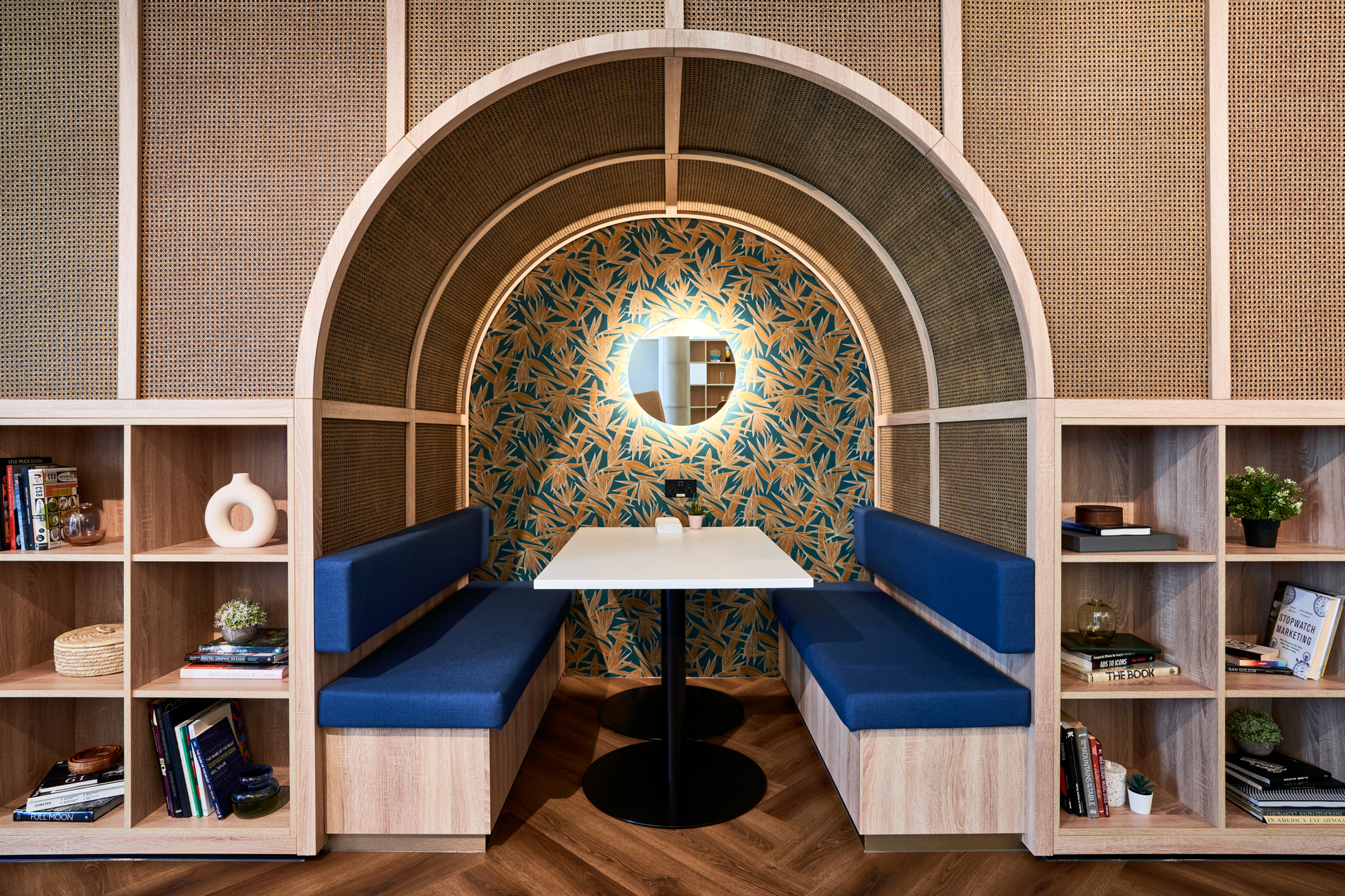 An intimate booth seating area with a stylish arch design and bookshelf at Publicis Sapient’s London office.