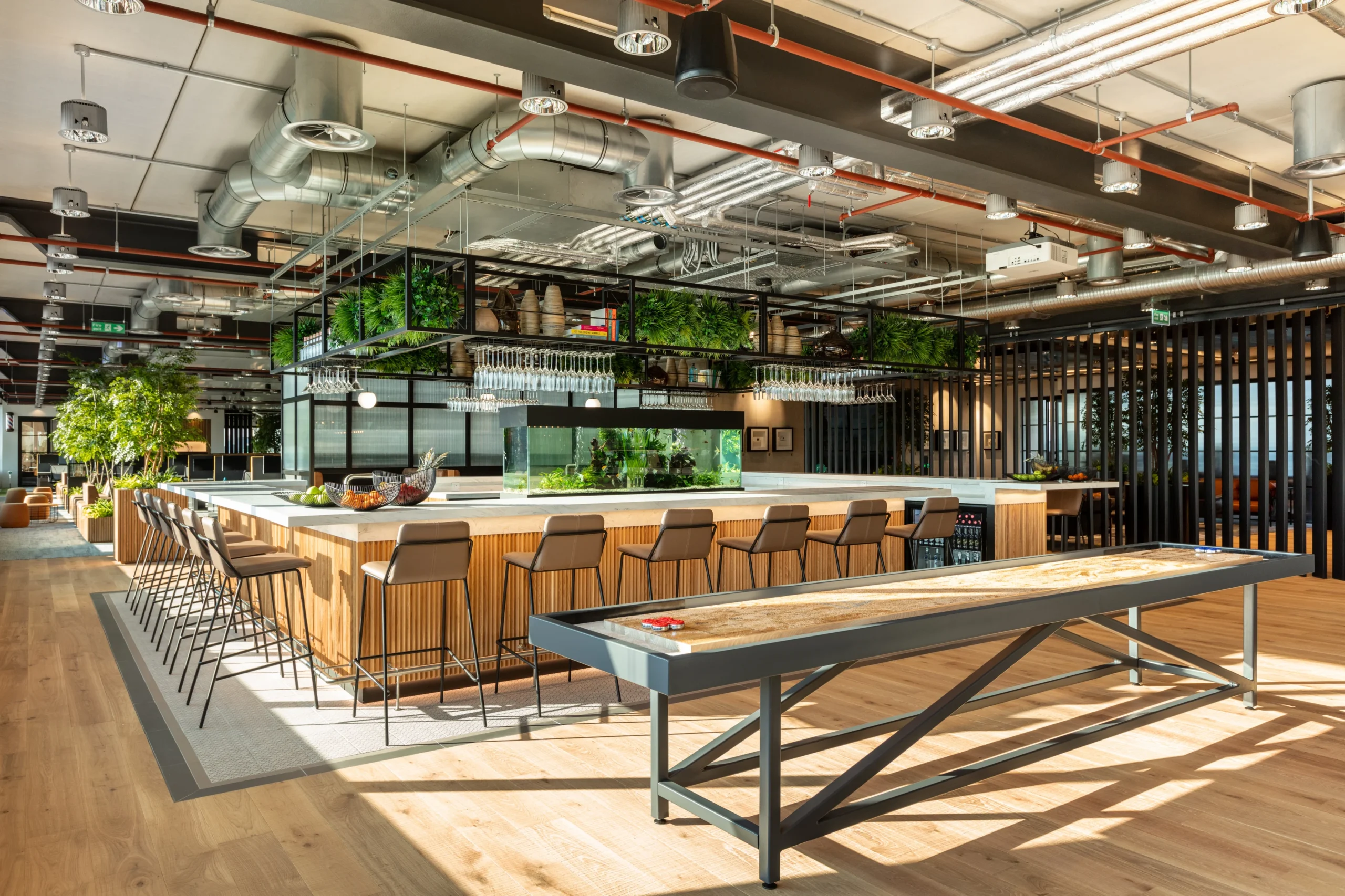 Alpha FX office by Design and Build Firm Modus, with a modern bar area, integrated greenery, industrial elements, and a spacious, inviting layout for employee interaction.