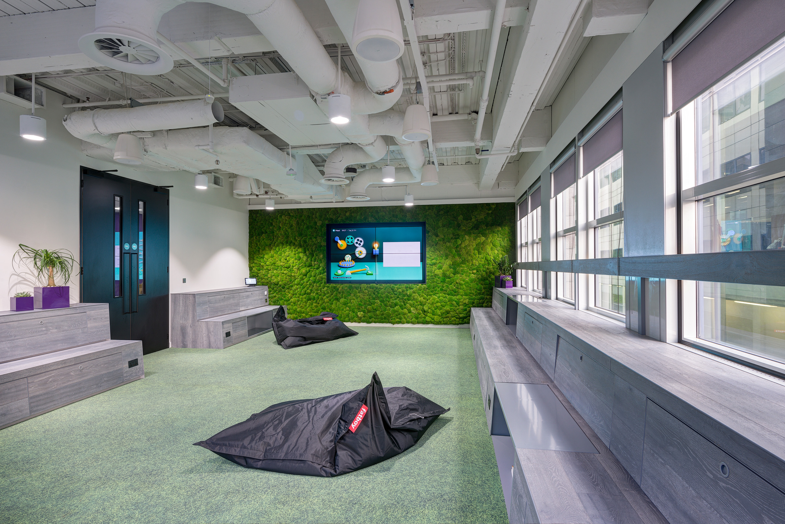 The amphitheatre area in Deliveroo’s London office, featuring tiered seating and a green living wall. Ideal for presentations and team gatherings, the space combines functionality with a touch of nature.