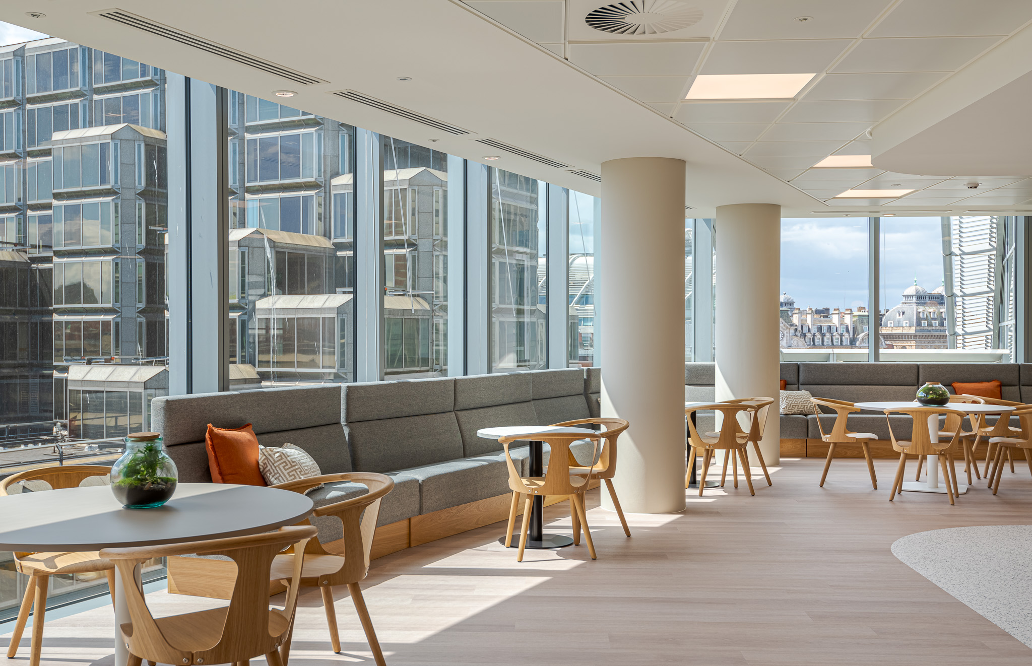 Bright and stylish communal dining area in Landsec's 100 Victoria Street Headquarters, designed by Modus Workspace. The area showcases a green living wall, sleek, orange-tiled counters, and ample seating for employees.