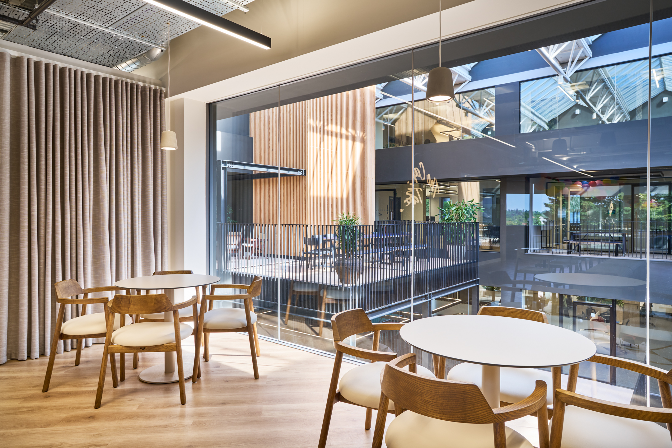 Overlooking the central courtyard, this breakout space at Nomad Foods offers a serene, secluded setting for team discussions, blending into the natural and modern elements of the workspace.