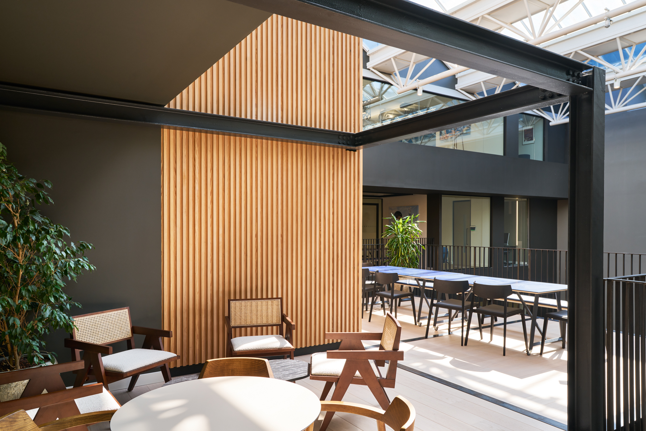 A courtyard seating area at Nomad Foods, featuring warm wood textures and natural light, is a perfect retreat for employees to relax or collaborate, inspired by Modus Workspace’s focus on well-being.