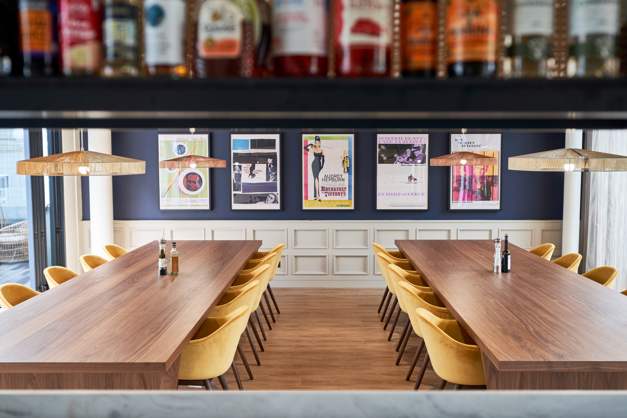 A large private dining room at a private equity firm in Marylebone, with a long wooden table and yellow chairs. Vintage movie posters line the walls, adding a touch of culture to this elegant space designed by Modus Workspace.