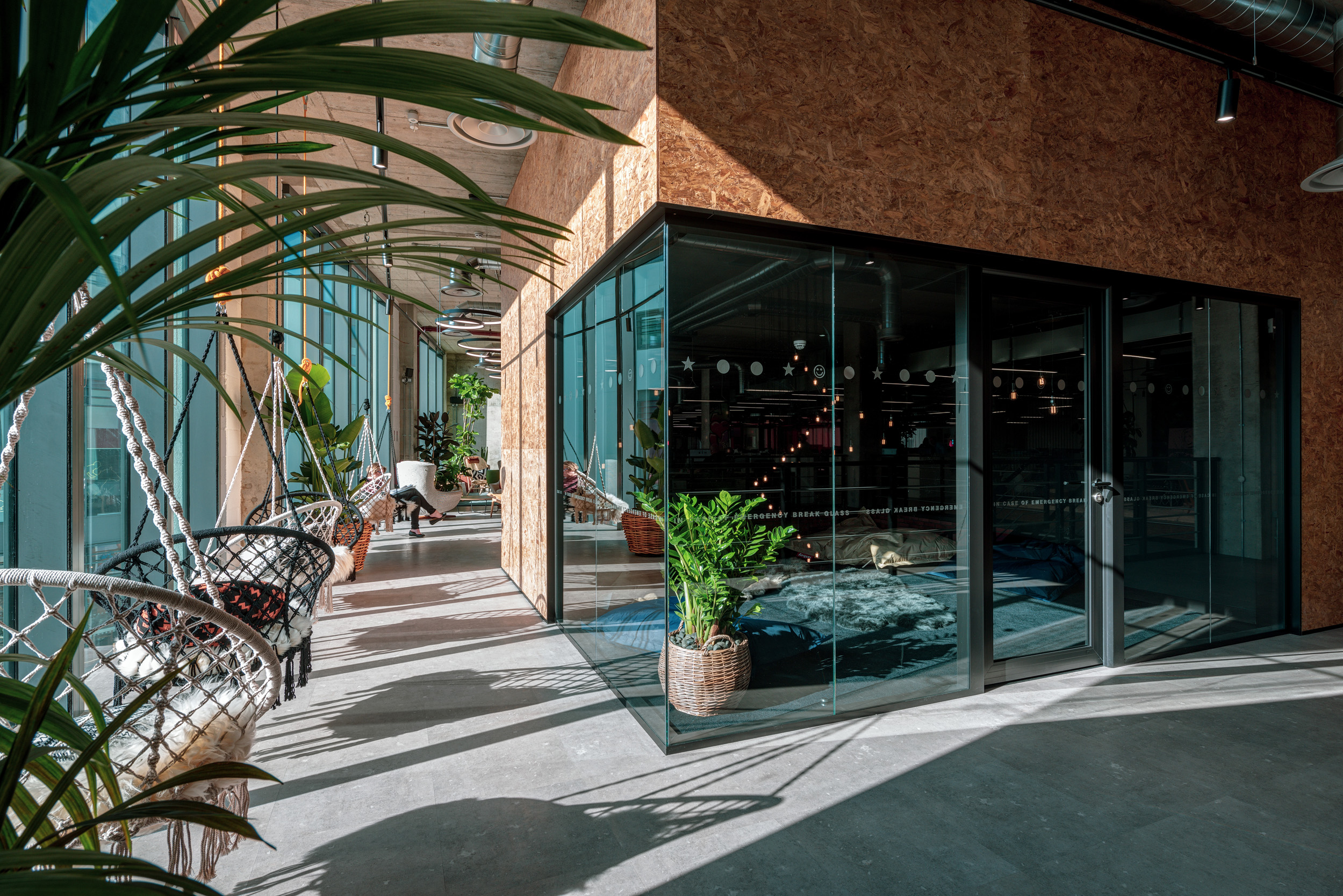 Studio 19’s award-winning coworking space at the International Property Awards, featuring bohemian hanging chairs, lush plants, and a modern glass-walled break-out space.