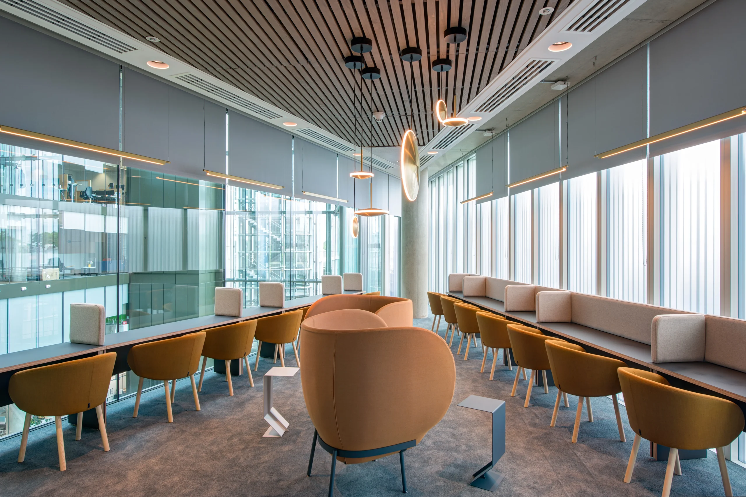 Quiet work lounge at Storey - 2 Kingdom Street, designed by Modus Workspace. Comfortable seating is paired with modern, stylish lighting, and large windows that offer a view of the surrounding building, fostering productivity and focus.