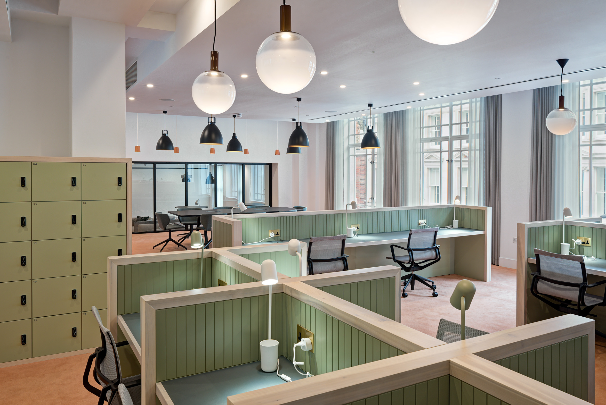 An open-plan workspace at The Office Group Wimpole Street, featuring individual desk pods and soft lighting. The space, designed by Modus Workspace, promotes productivity with its modern layout and neutral green and beige colour palette.