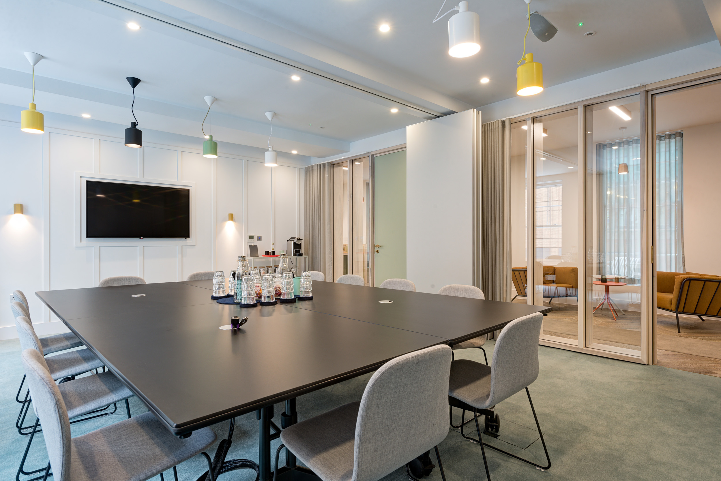 A sleek meeting room at The Office Group Wimpole Street, designed by Modus Workspace, featuring a long table with elegant lighting. The modern setting is equipped with technology for presentations and discussions.