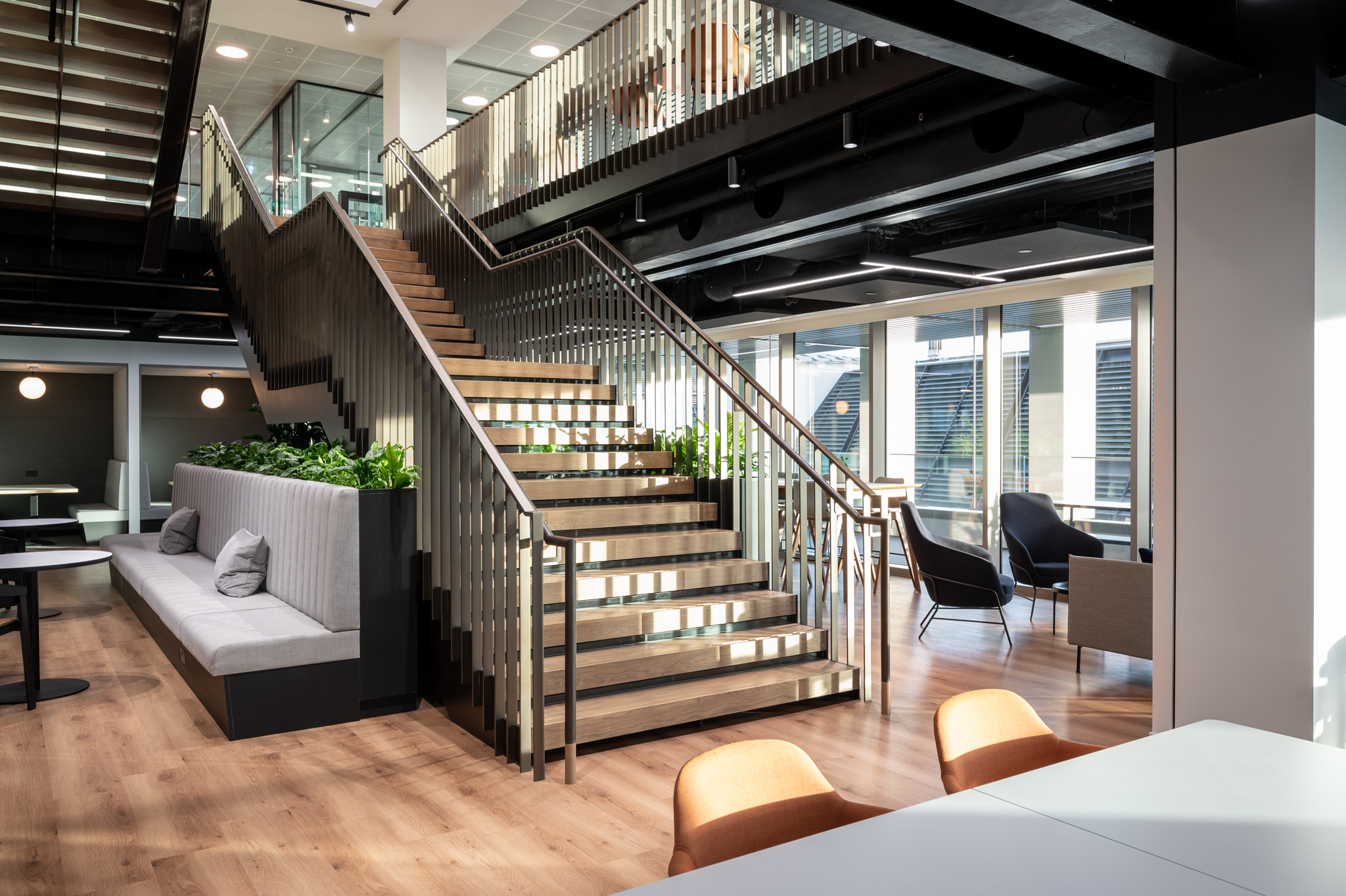 The staircase and collaborative space at Numis, part of the Mixology Awards 2022 Project of the Year, featuring modern design with natural light, open seating areas, and biophilic elements, designed by Modus.