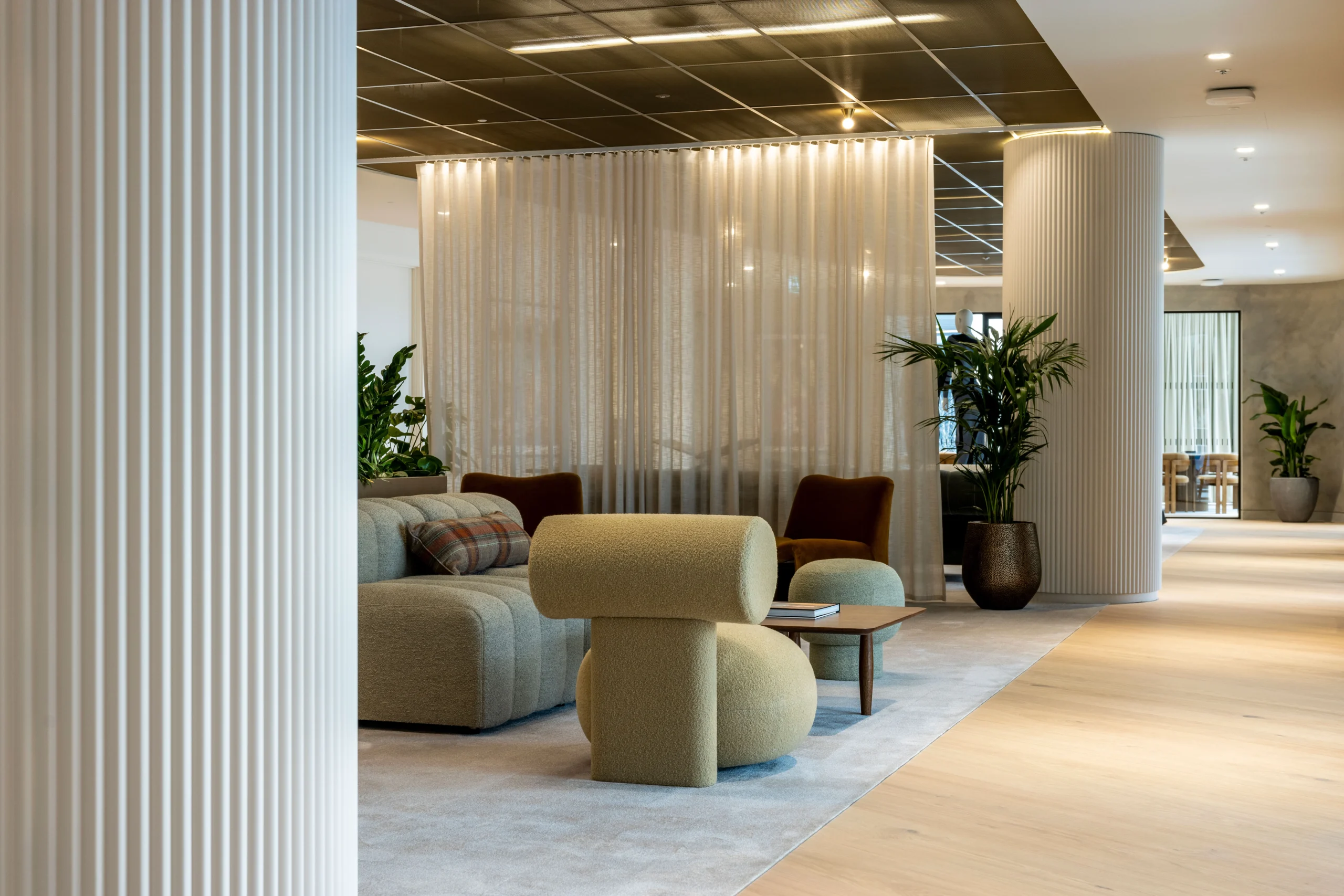 A meeting room at Authentic Brand Group, designed by Modus, with a long conference table, beige chairs, and floor-to-ceiling windows allows natural light to flood the space.