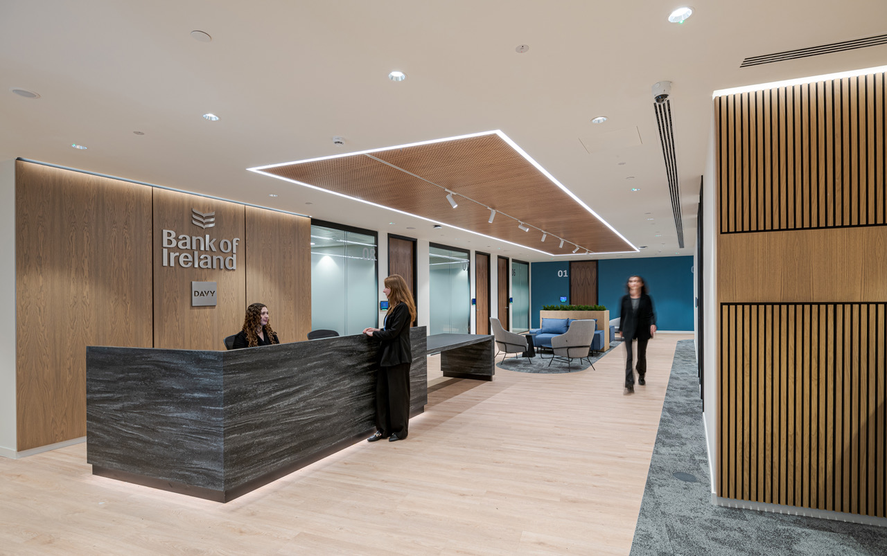 The sleek reception area of Bank of Ireland, designed by Modus Workspace, with wood-panelled walls and a marble front desk, creates a welcoming entrance.