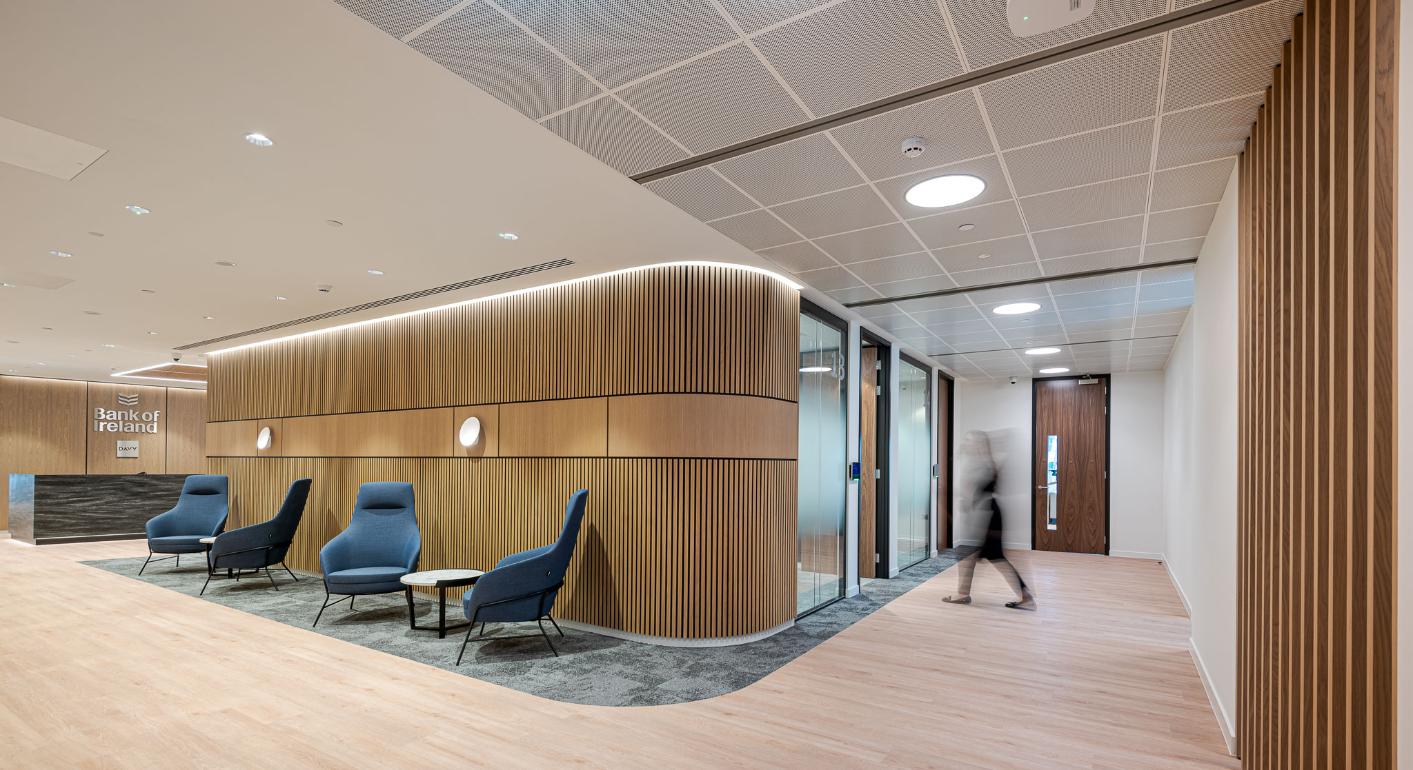 The hallway at Bank of Ireland, designed by Modus Workspace, features elegant wood finishes and contemporary seating leading to meeting rooms.