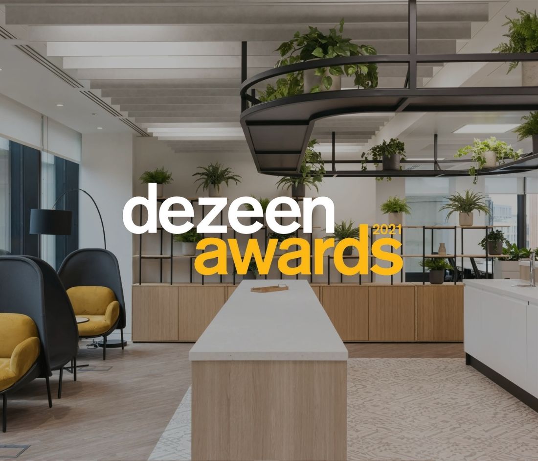 Dezeen Awards 2021 logo overlaying an interior image of the London and Oriental project, featuring modern design elements with abundant greenery, sleek furniture, and an open workspace layout.