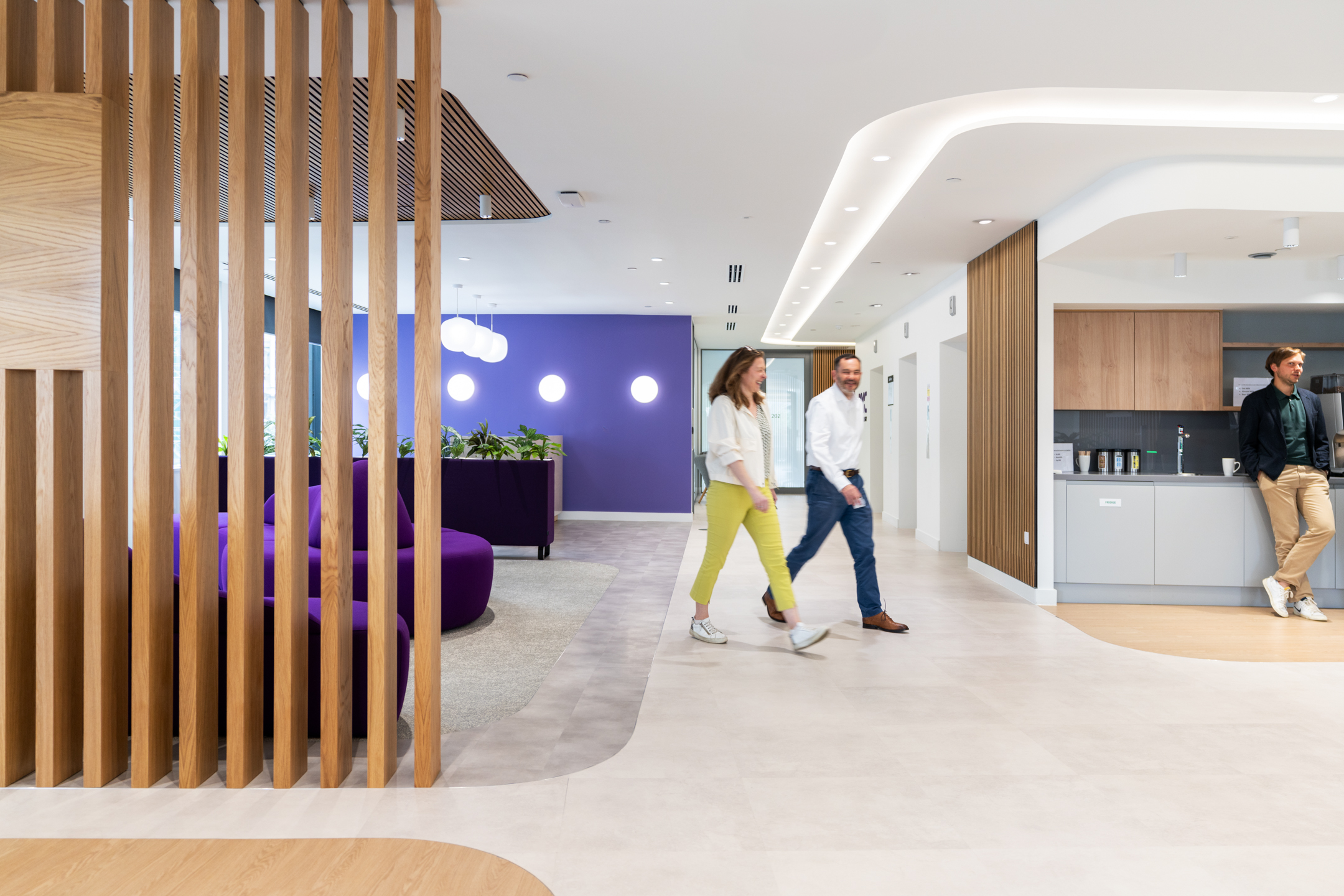 DXC Technology's open meeting space, with purple lounge chairs, wooden panel dividers, and soft lighting.