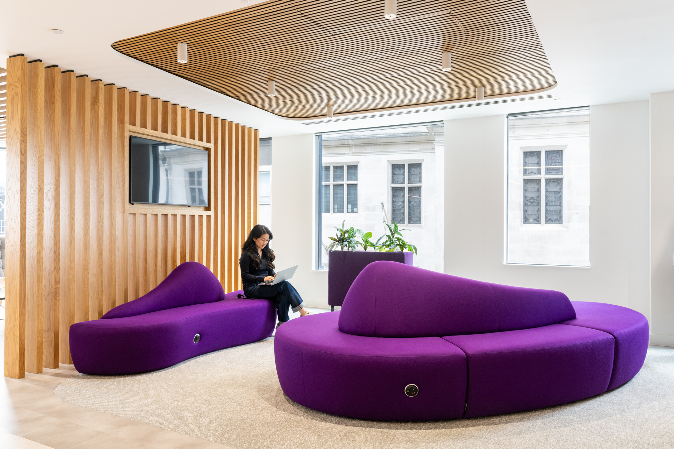 A breakout area at DXC Technology featuring unique purple lounge seating and wooden ceiling panels.