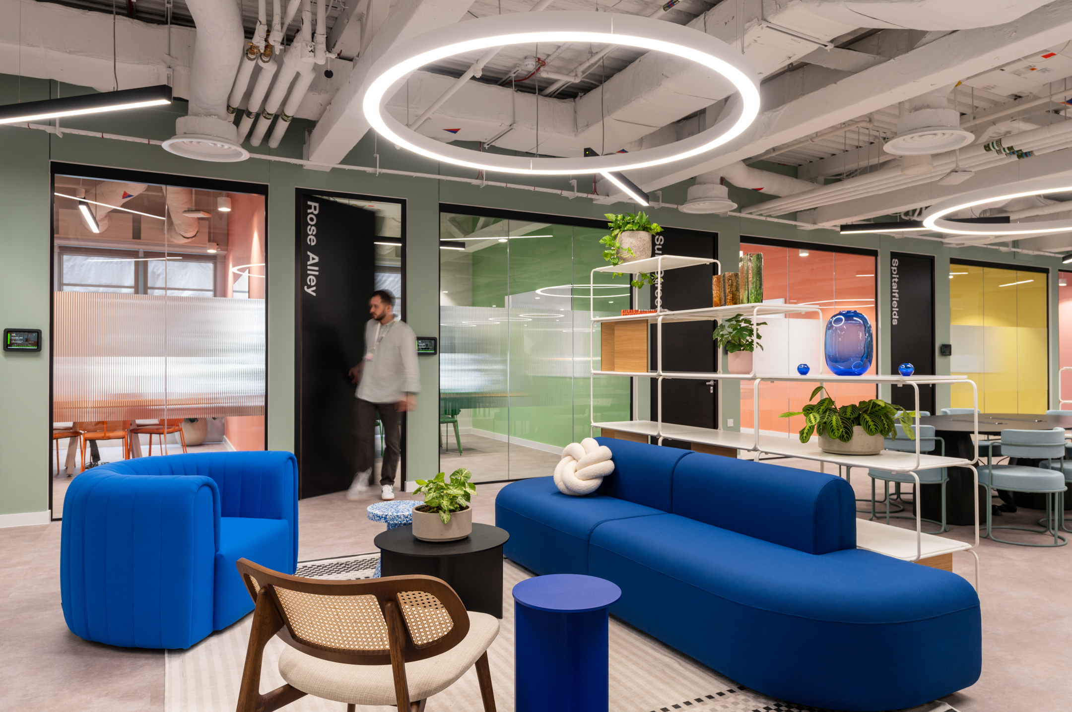 Bold blue seating and soft furniture in a breakout area at Huckletree Bishopsgate, surrounded by glazing partitioned rooms named after London streets.