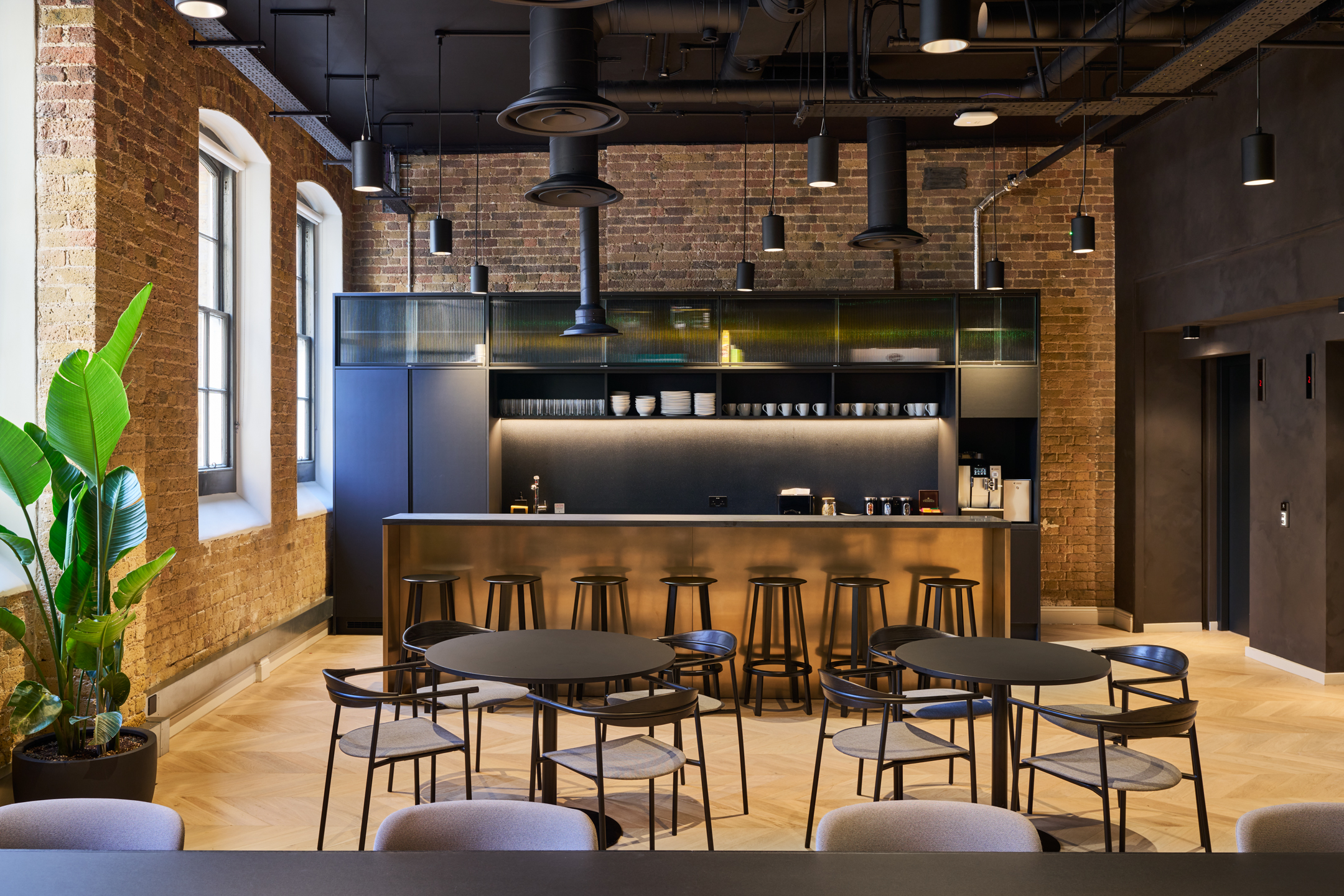 Contemporary teapoint at Lotus's new headquarters, designed by Modus, with exposed brick walls and sleek modern furnishings within the Ragged School.