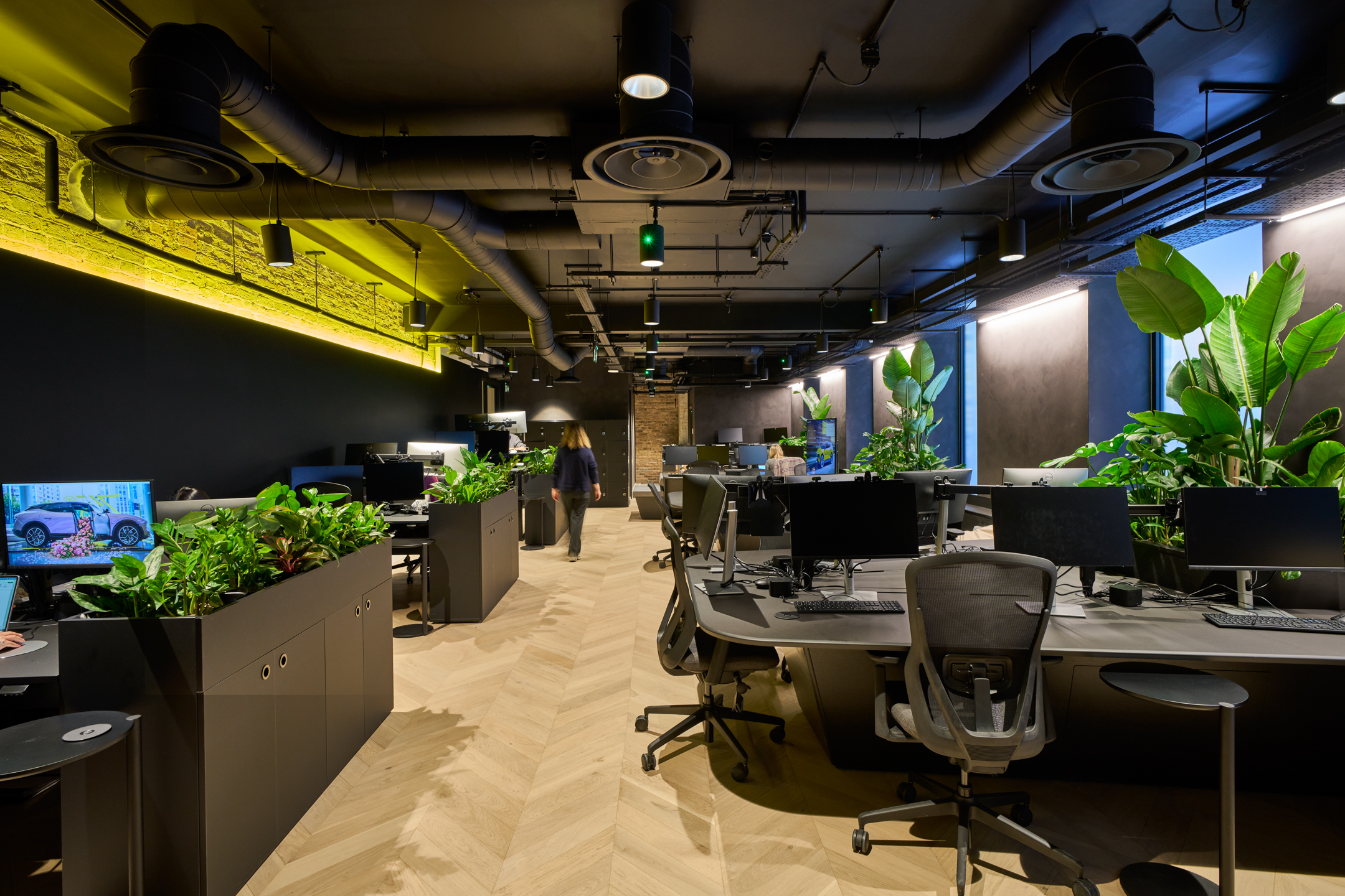 Lotus's open-plan workspace, designed by Modus, with a focus on natural lighting, green plants, and modern office furniture set within the industrial architecture of the Ragged School