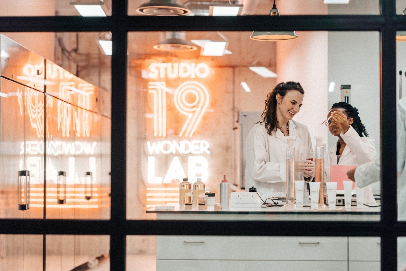 A vibrant laboratory space designed by Modus Workspace for SLG, featuring a neon sign that reads 