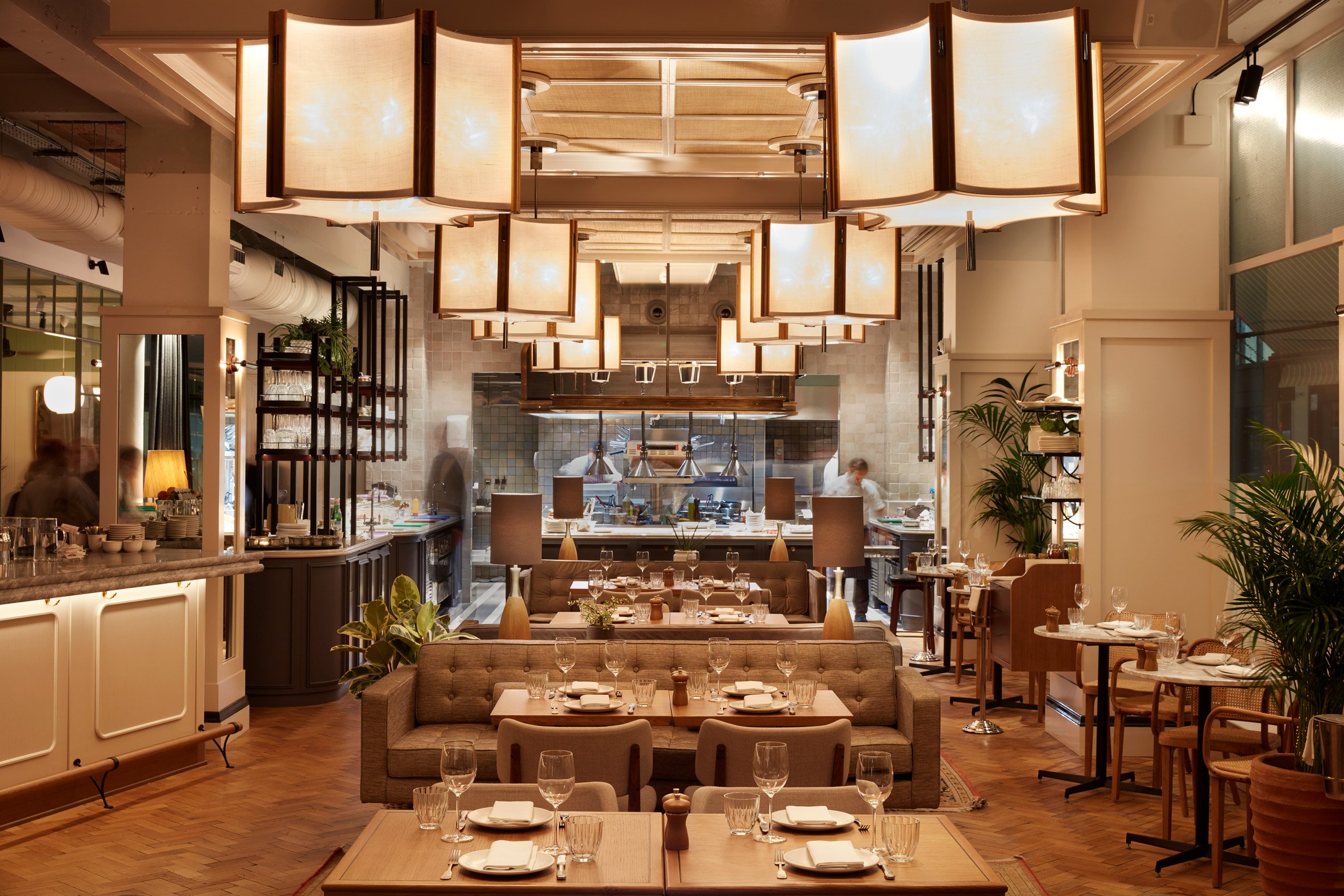 An elegant dining area at a private members' club in Fitzrovia, designed by the leading design and build firm Modus, has a warm, inviting atmosphere and open kitchen views.