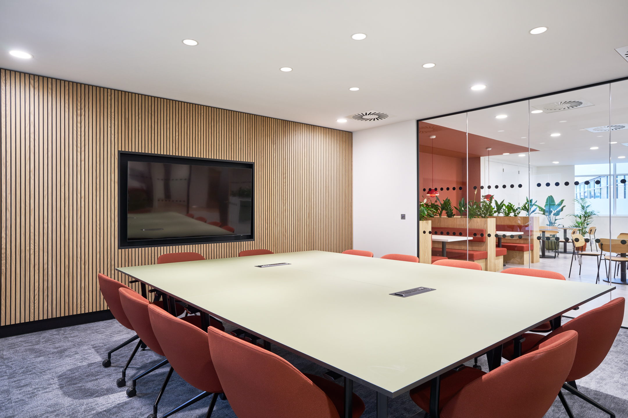 Meeting Room featuring a Mounted TV Screen, a Green Table, and Brown Chairs