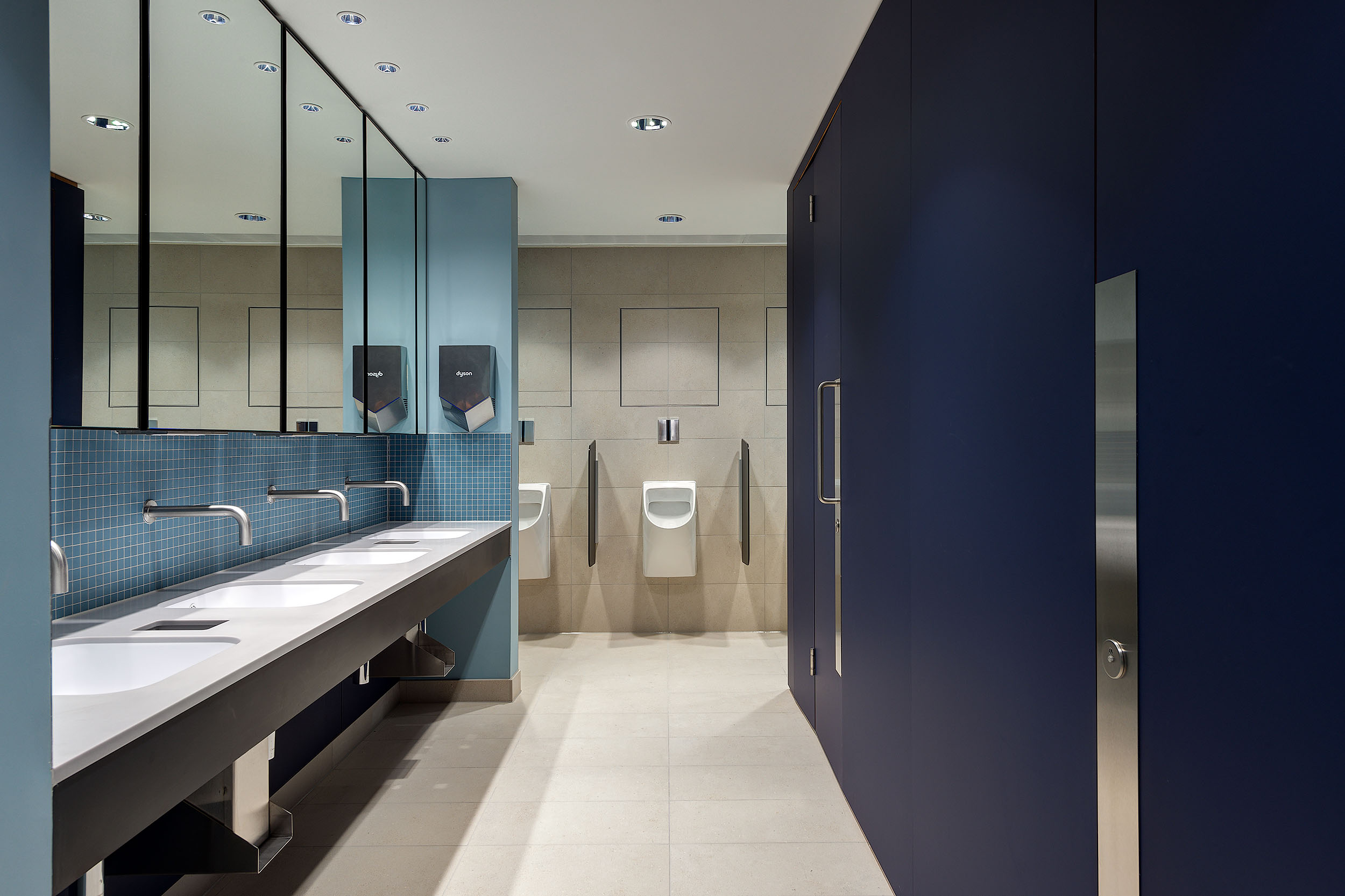 Bathroom at Chiswick Business Park Building 3, featuring modern fixtures, minimalist design with deep blue and grey tones, and mirrored walls for a sleek, contemporary look.