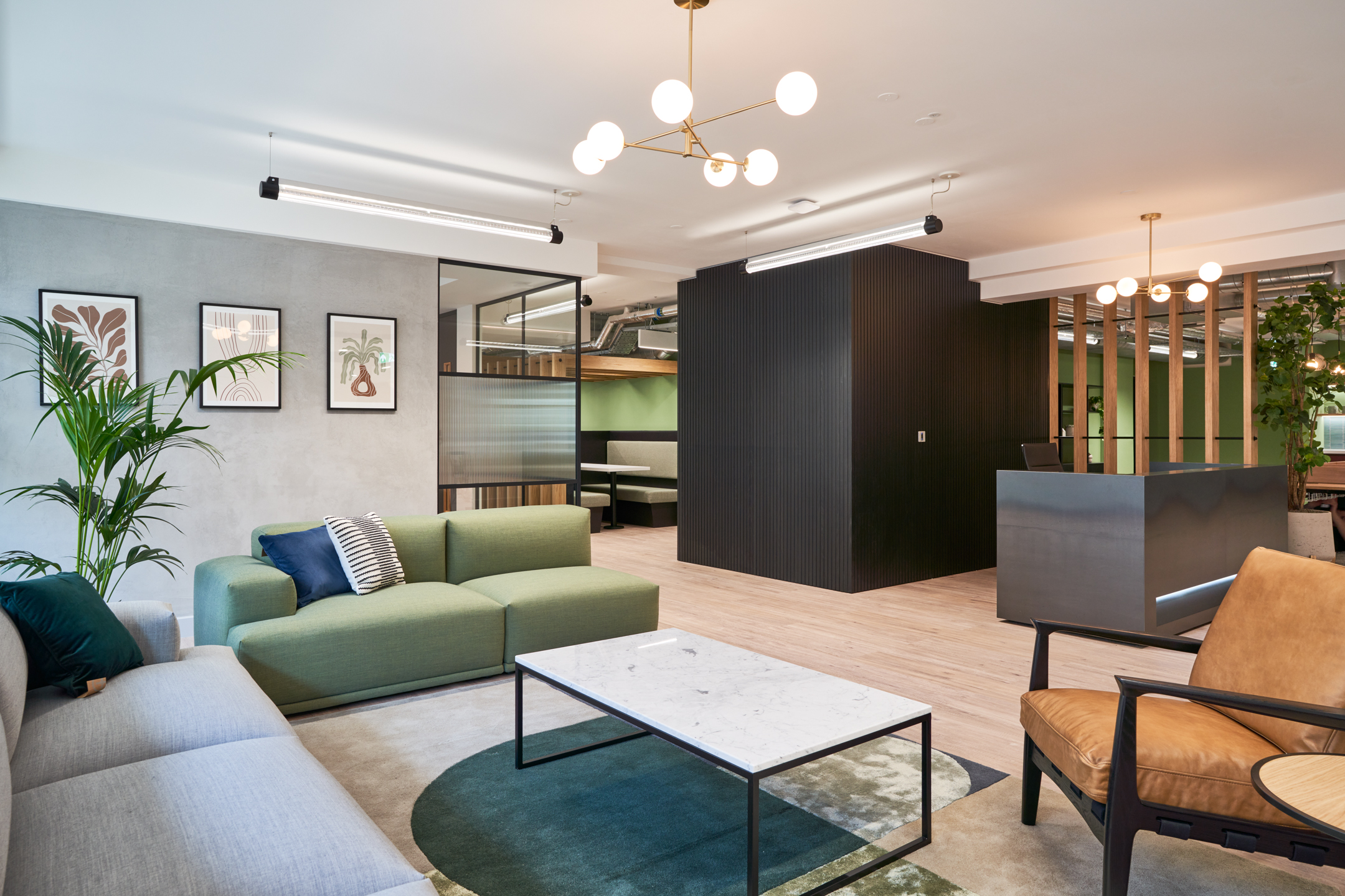 Multi-coloured seating area with a green and grey sofa, sleek lighting and glass partions