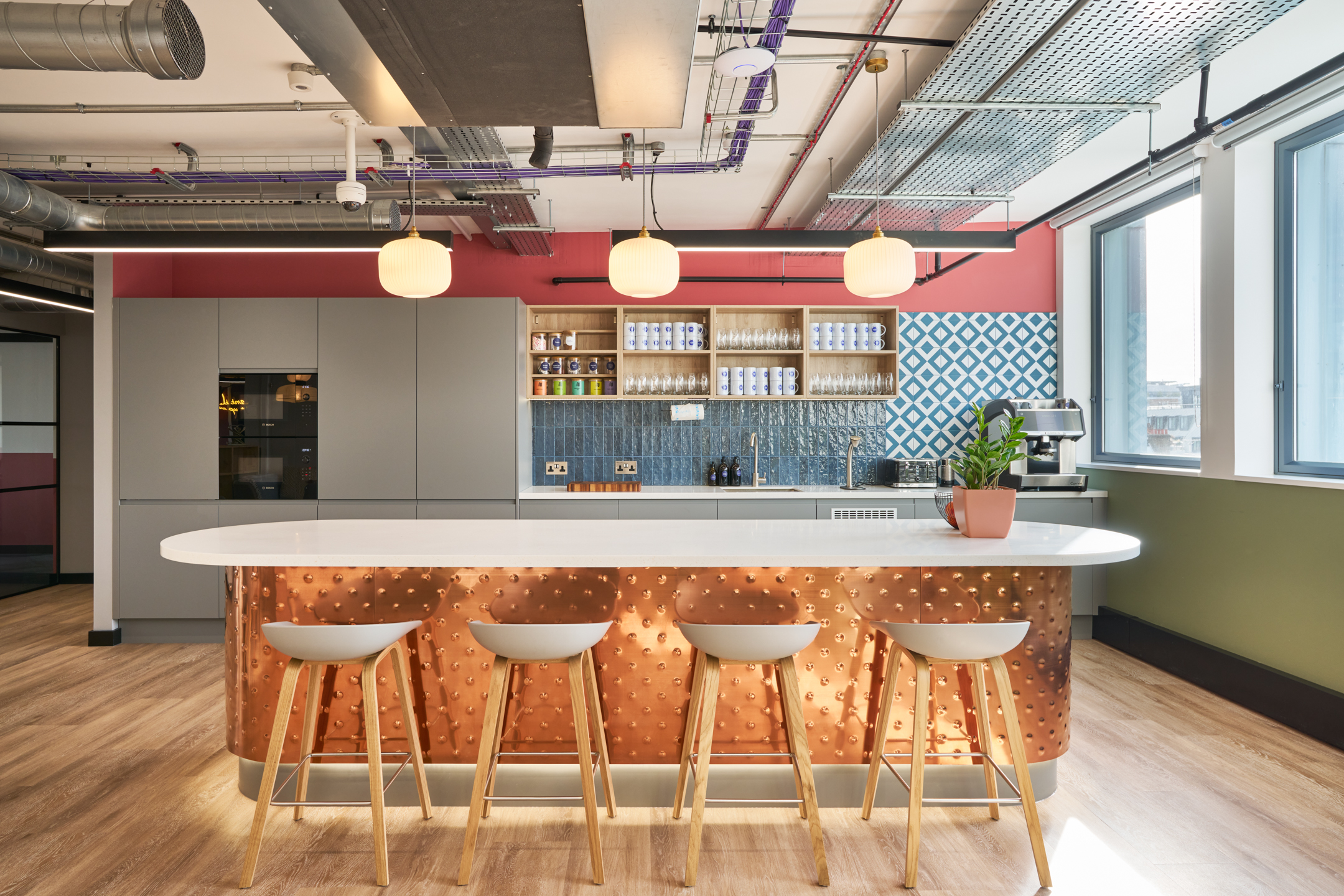 The teapoint at Work.Life's Waverly House, featuring a copper island with bar stools, bold patterned tiles, and vibrant colours in a modern coworking space.