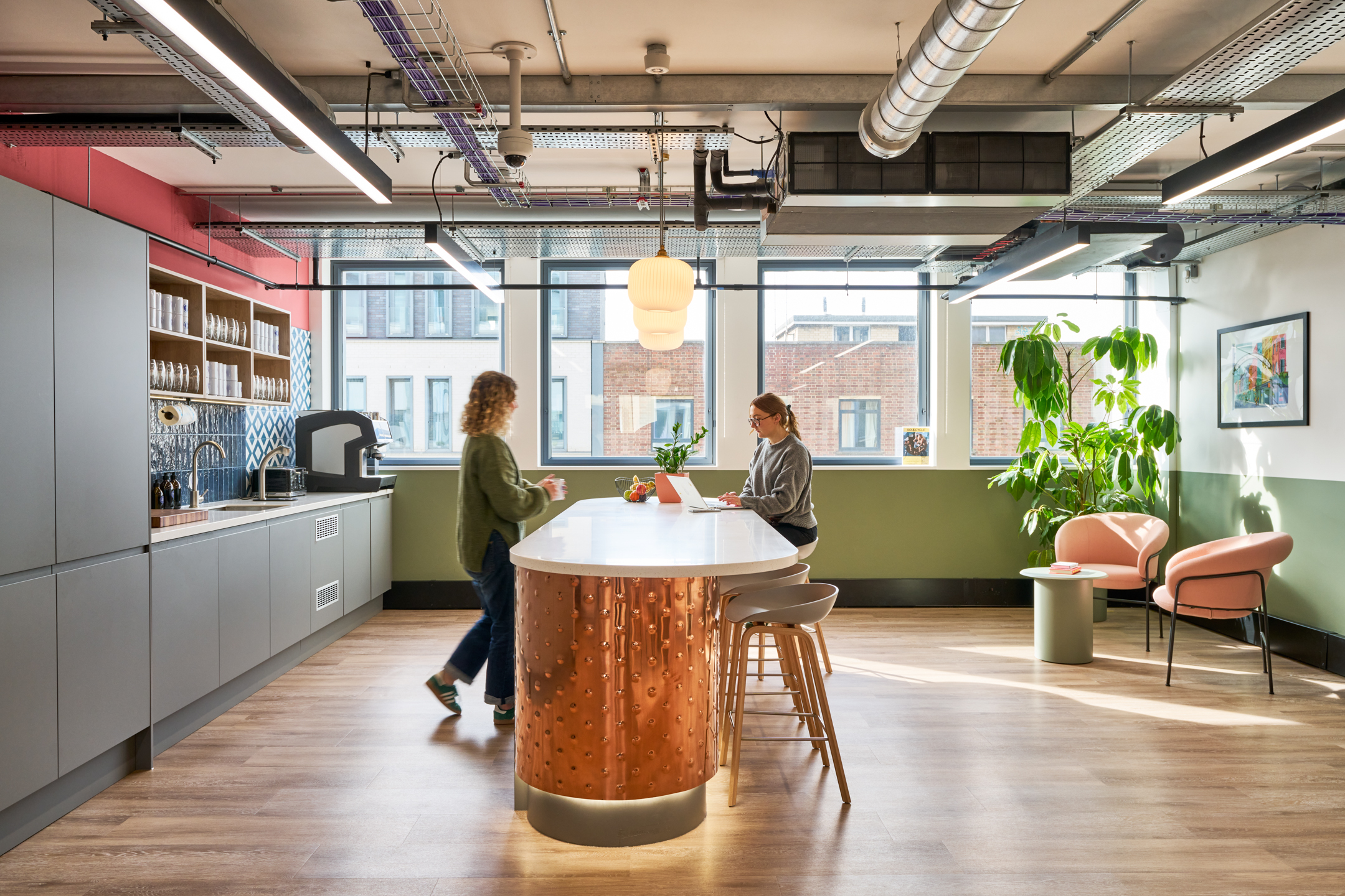 The social teapoint at Work.Life's Waverly House, featuring a copper island, modern cabinetry, ample natural light, and comfortable seating for collaboration.