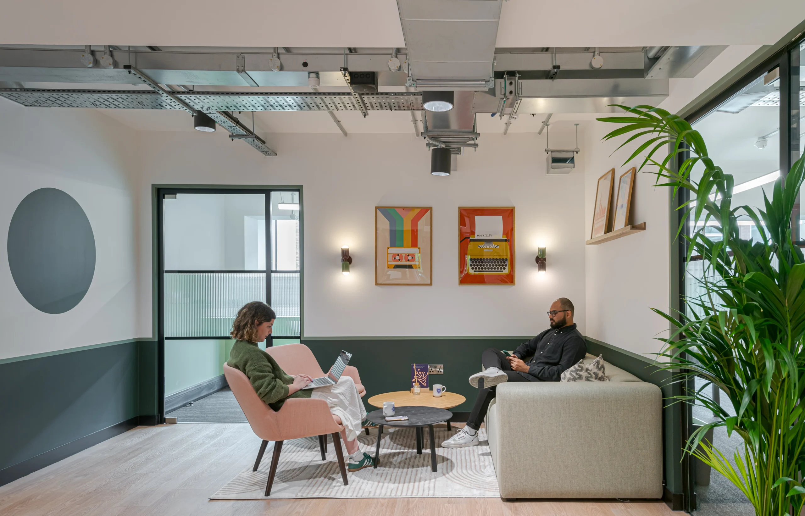 A cosy lounge area at Work.Life’s Typewriter Building, featuring colourful typewriter artwork, modern seating, and a mix of greenery and contemporary decor.