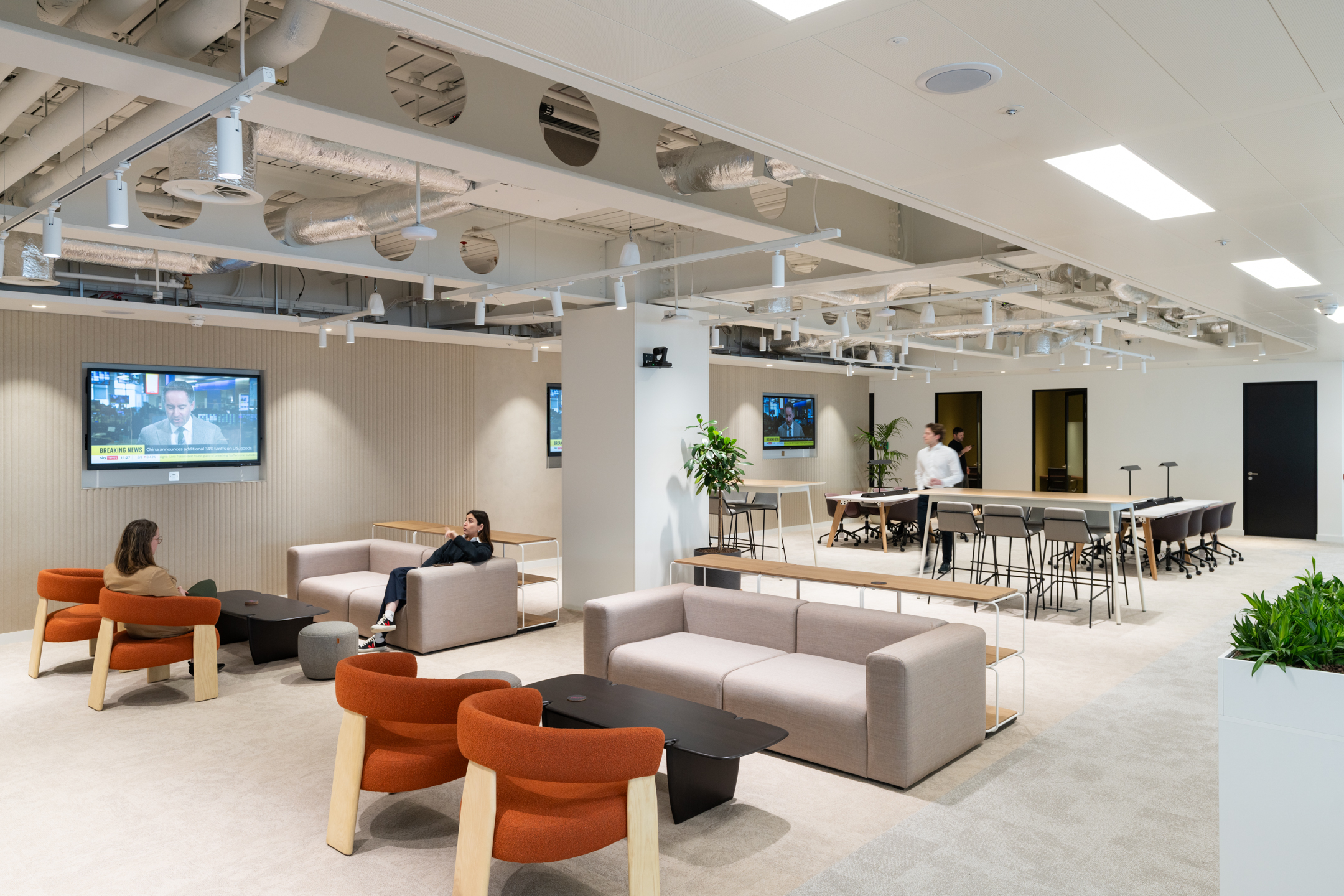 Spacious lounge and breakout area in the Ark Syndicate office, with soft seating, collaborative work tables, and integrated media screens.