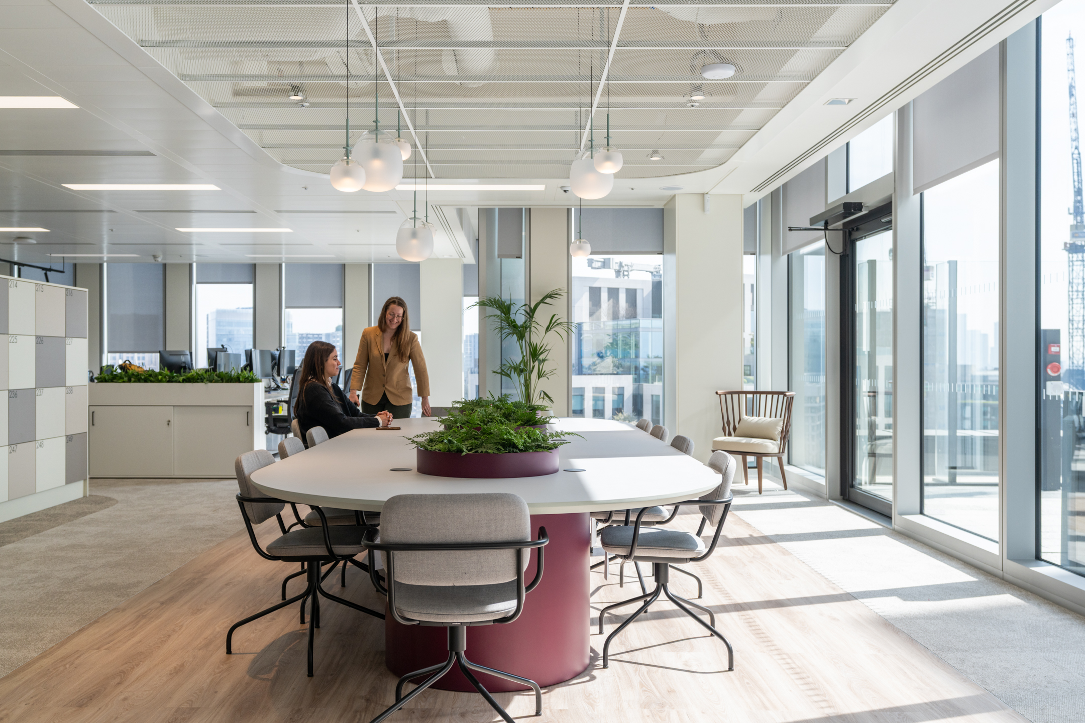 Bright and airy meeting space at Ark Syndicate featuring a round collaborative table with integrated planting, natural light, and city views through full-height glazing.