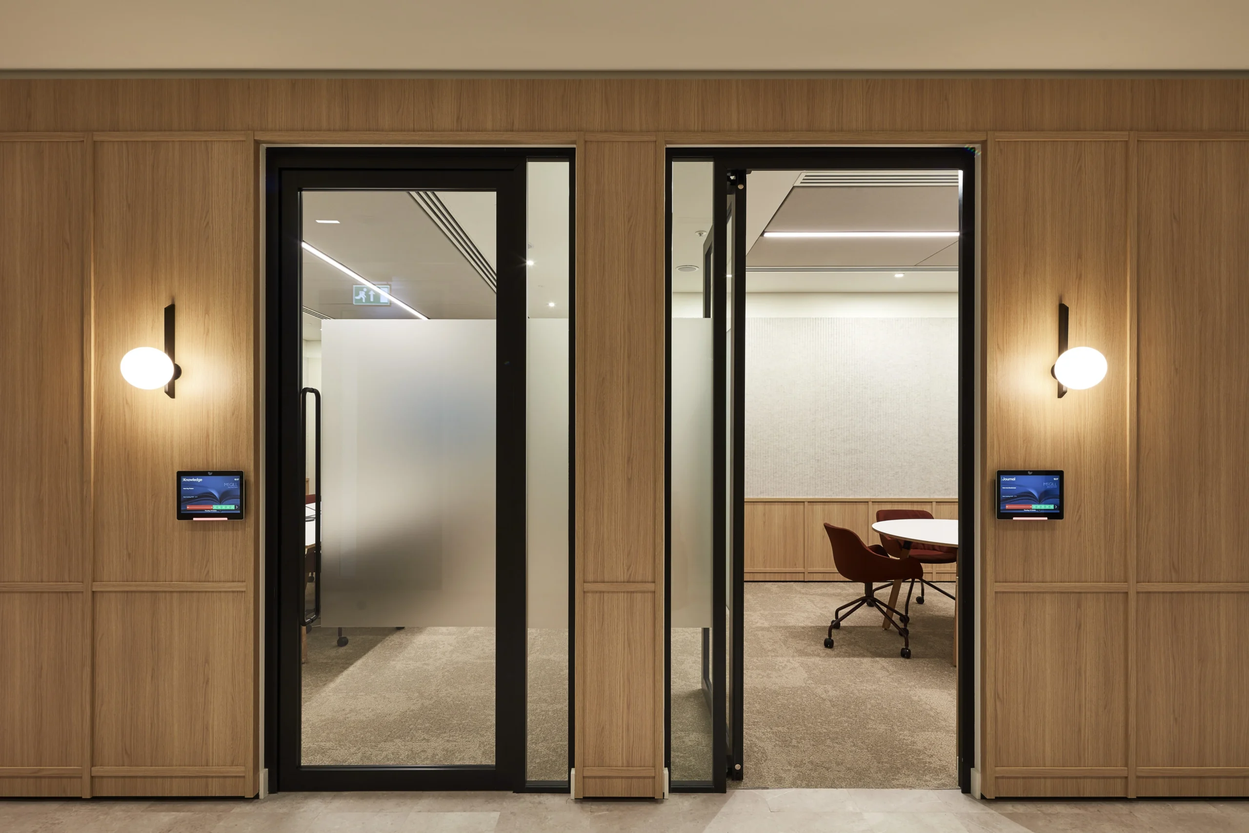 Glass-fronted meeting room viewed from the outside, showcasing modern interior design and visual connection to adjacent workspaces