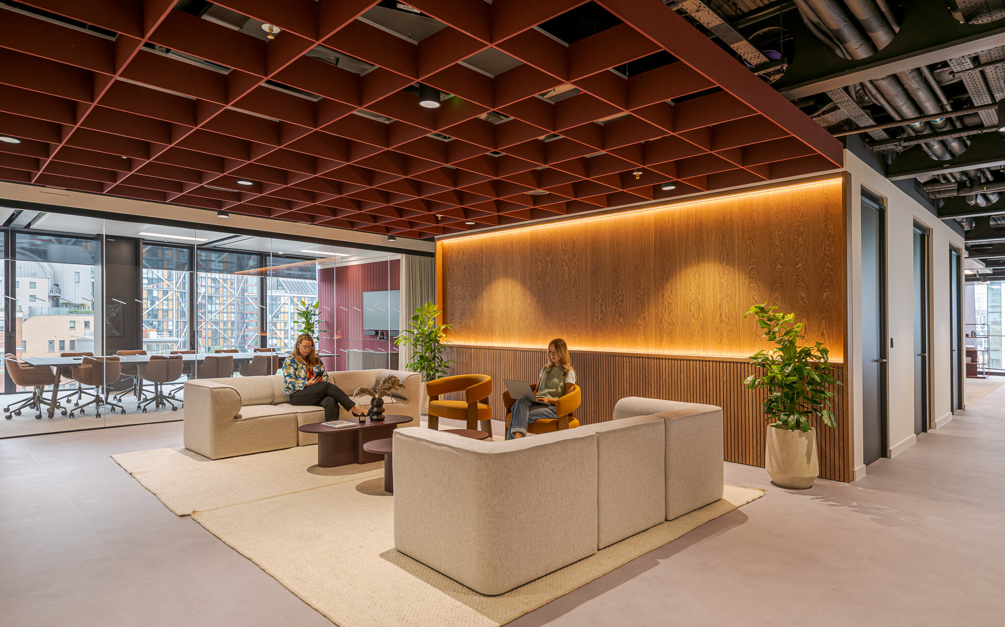Arbor reception lounge with warm timber finishes, grid ceiling detail and soft seating next to glass-fronted meeting room.