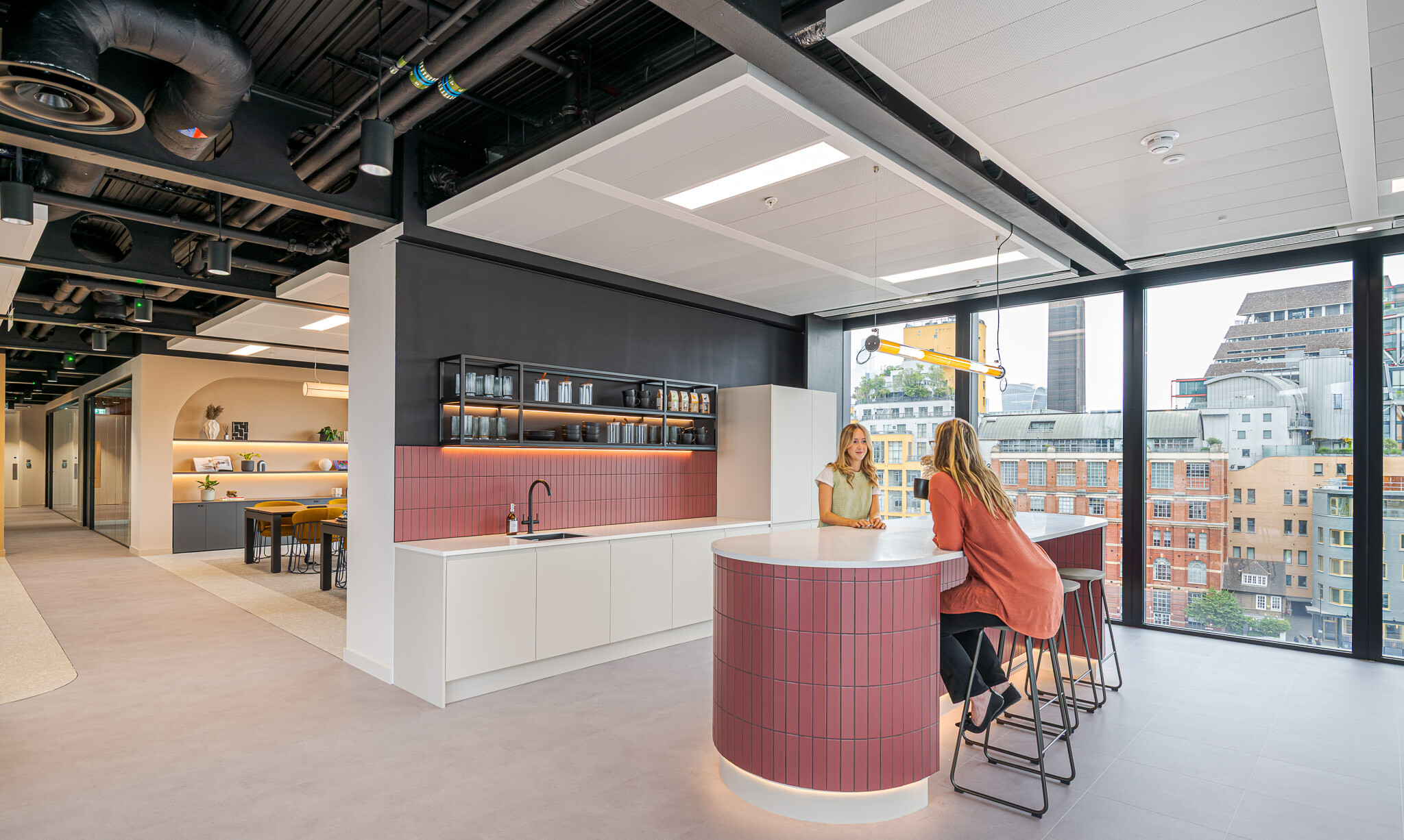 Bright teapoint space at Arbor with curved tiled island, open shelving and views over London architecture.