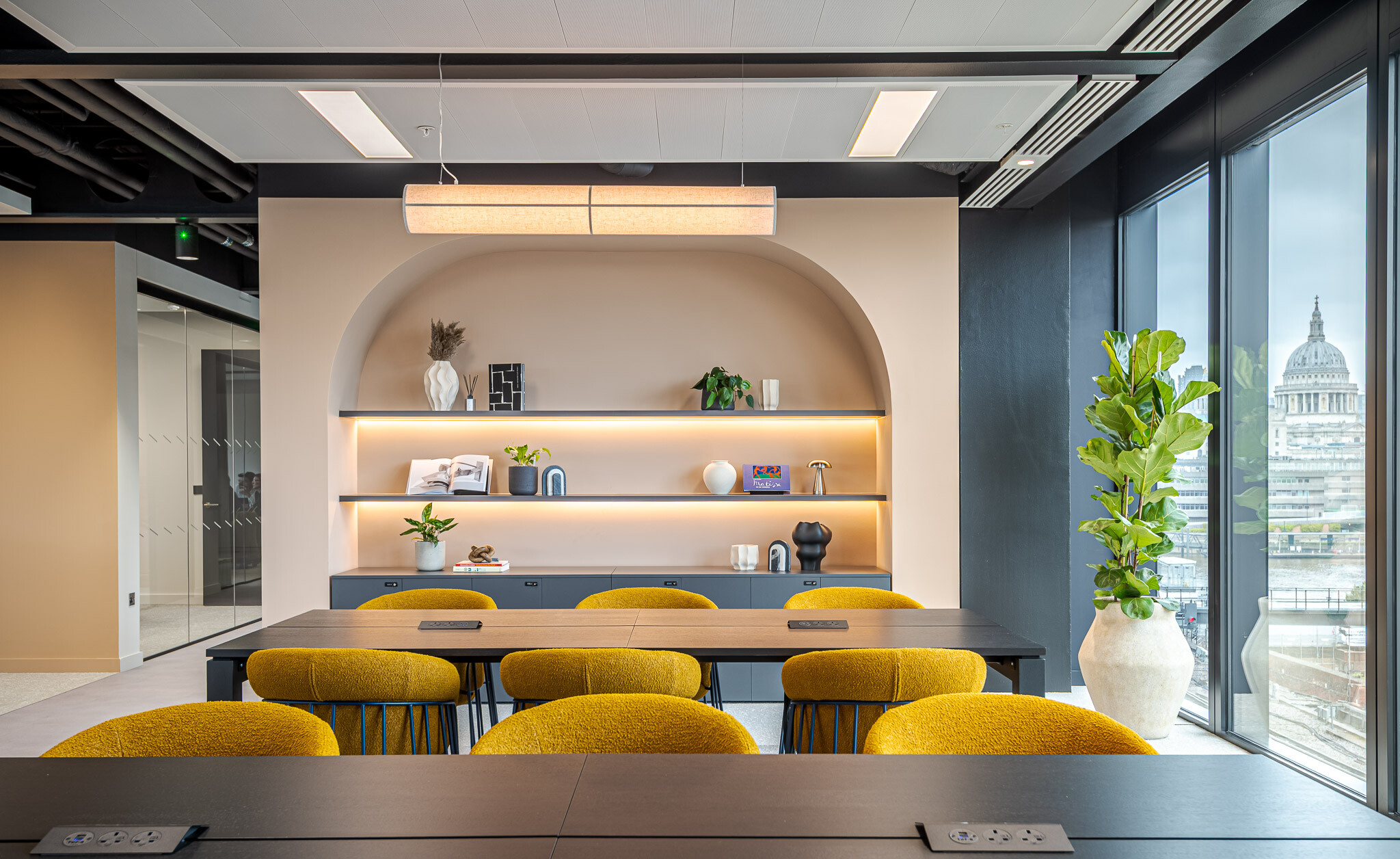 Workspace at Arbor with mustard chairs, arched shelving niche and views of St Paul’s Cathedral.