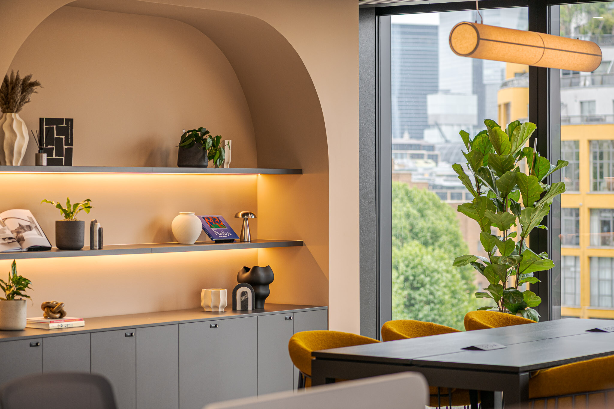 Shelf styling and greenery at Arbor with arched wall niche, curated objects and city views through floor-to-ceiling glazing.