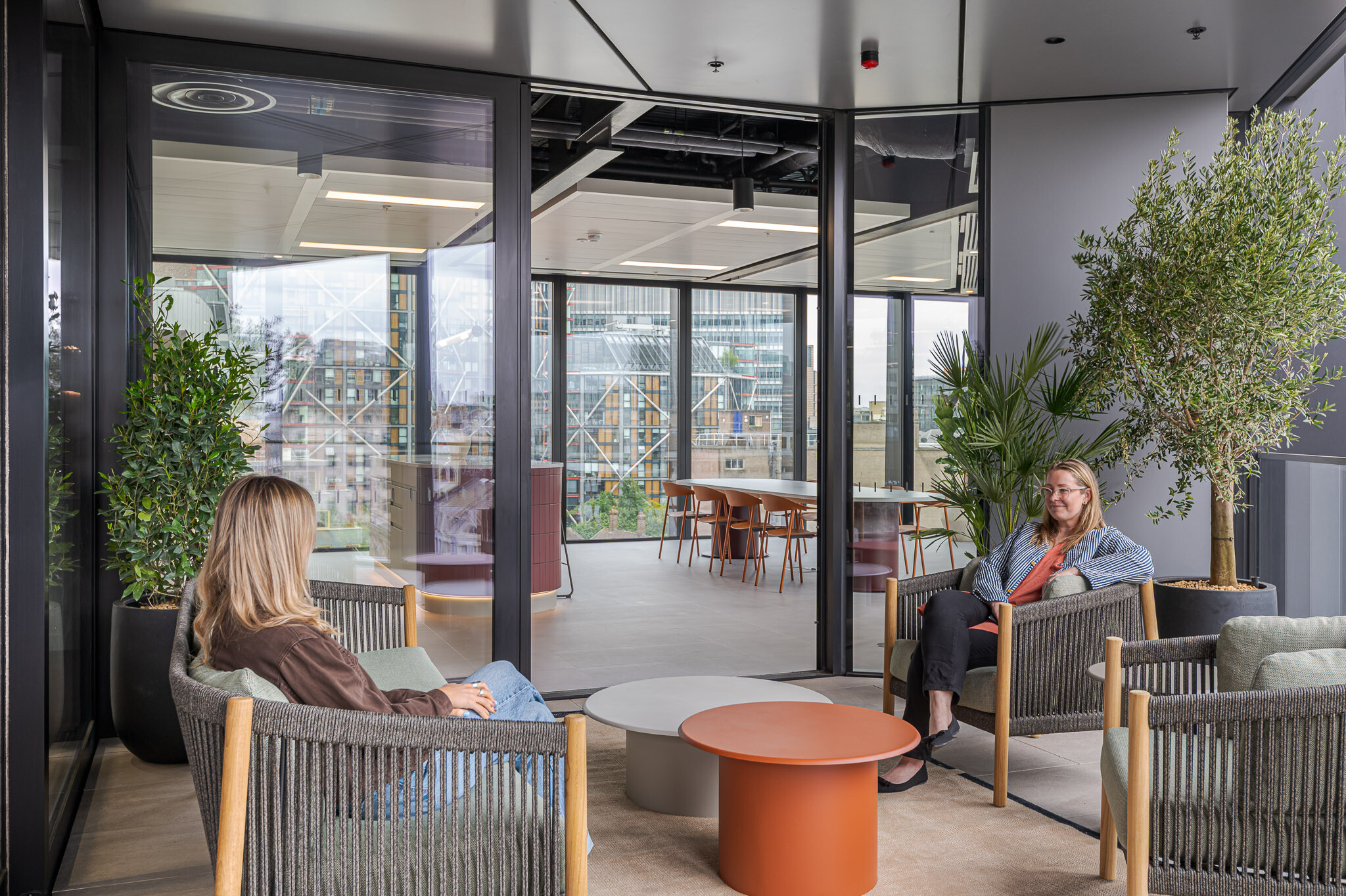 Outdoor terrace at Arbor with lounge seating, greenery and a view into the interior kitchen and breakout area.