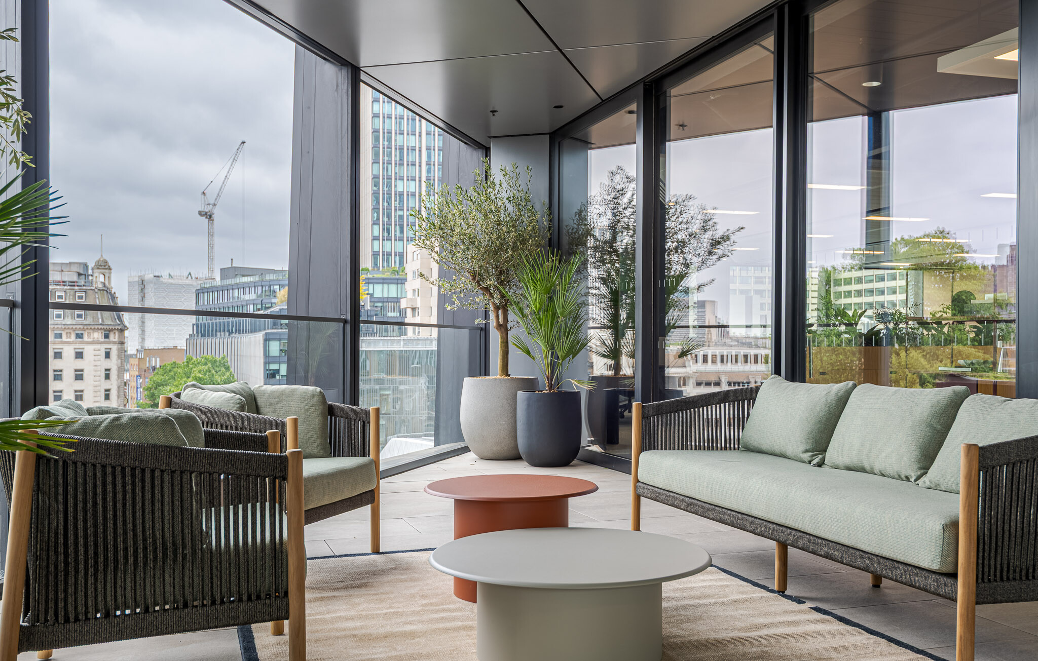 Outdoor terrace seating at Arbor with soft lounge furniture, potted plants and views over London skyline.