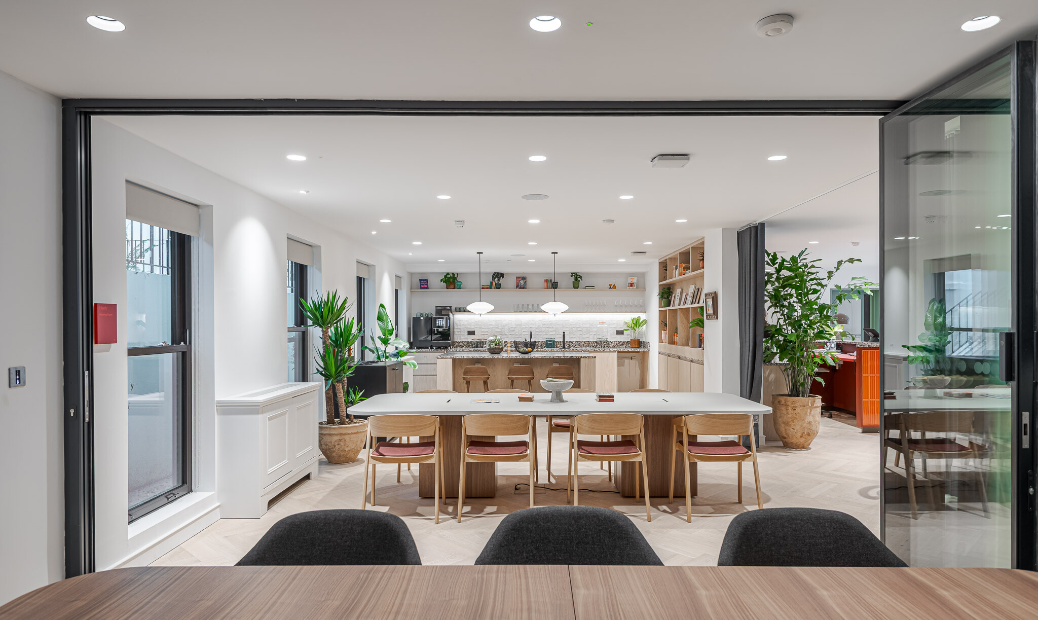 View from meeting room into multifunctional space at Bloomsbury House with open folding walls, shared table and teapoint in the background.