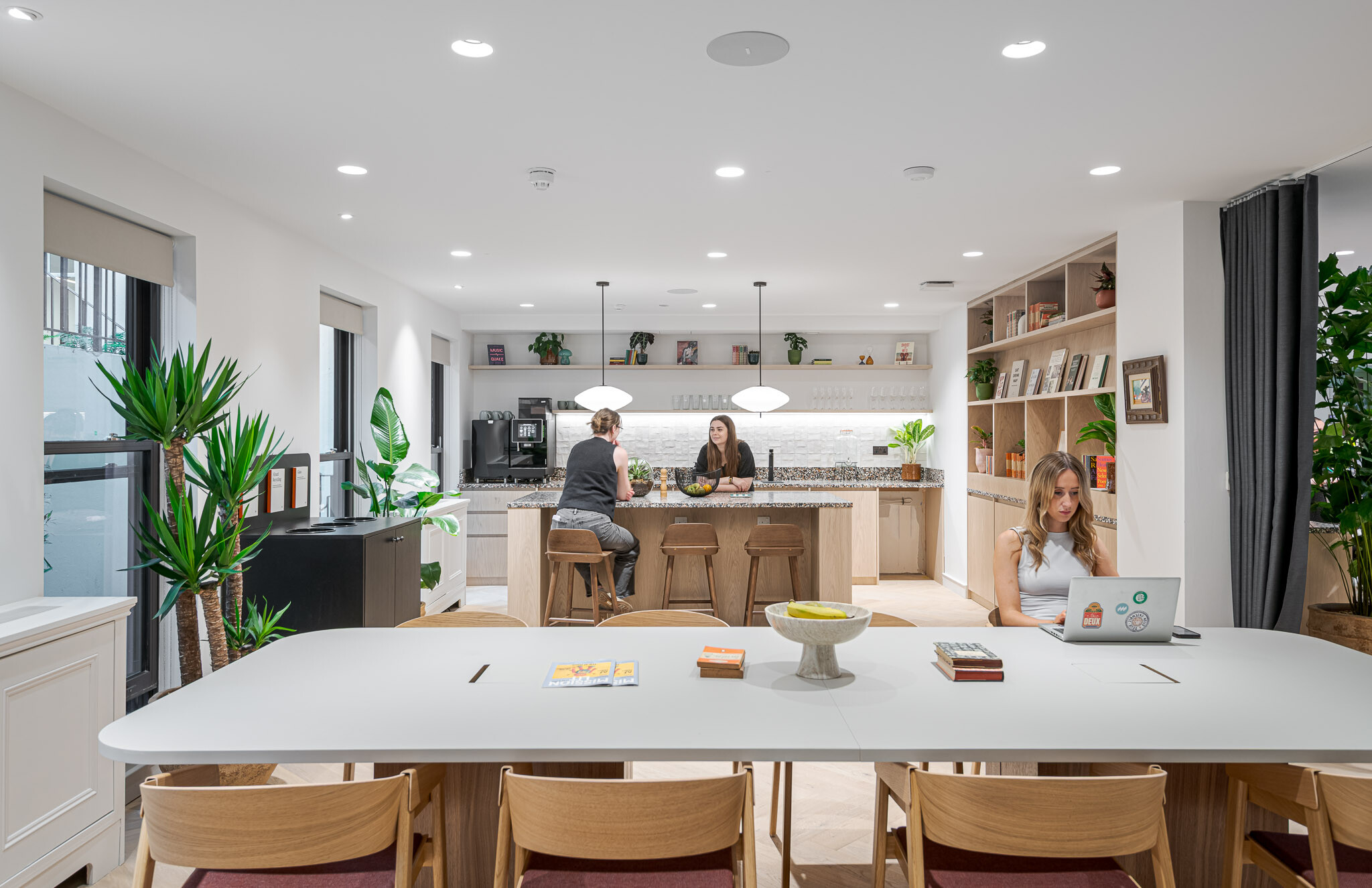 Multifunctional area at Bloomsbury House with a central teapoint, communal table, open shelving and soft planting.