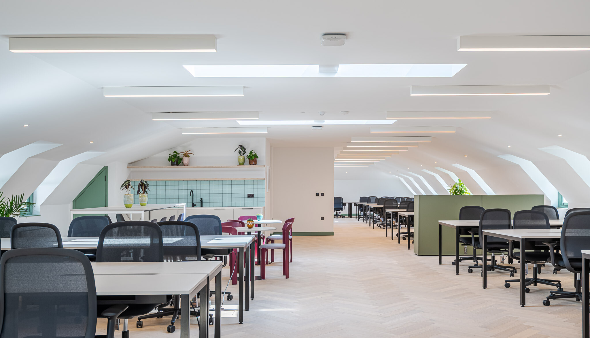 Open-plan office at Bloomsbury House with workstations, skylights and a soft green teapoint featuring pastel tiling.