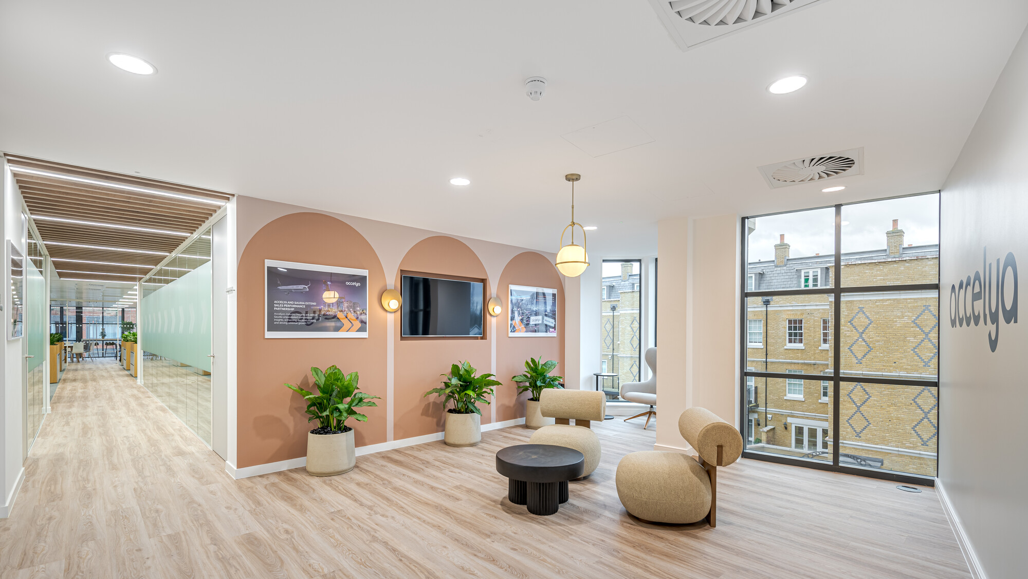 Reception area in Accelya's office by Two, with beige lounge seating, a black coffee table, and potted plants.