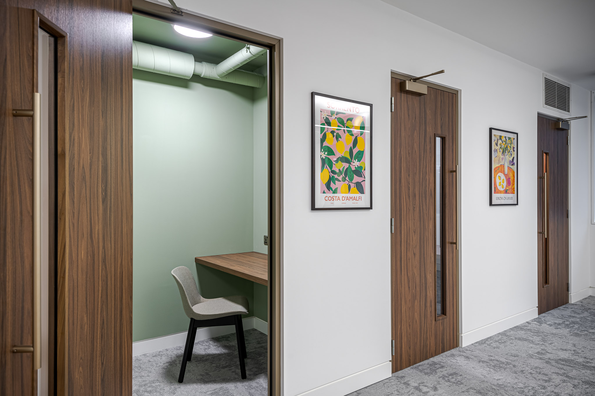 Acoustic phone booths in the Asset Management Firm's Tenant-Ready™ space, designed with timber doors, soft green interiors, and playful wall art for a quiet yet characterful workspace solution.