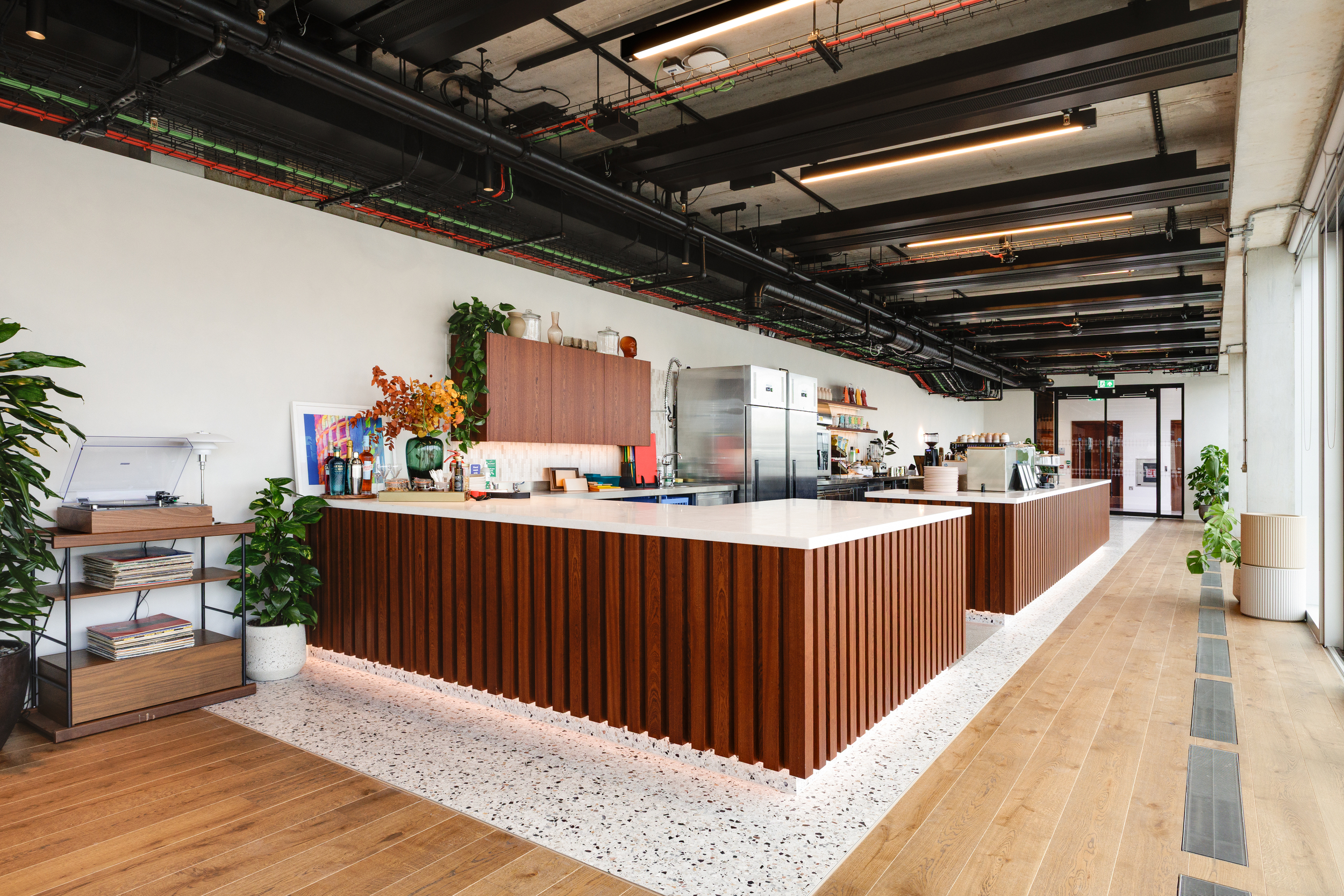 Bar and lounge area at the Space House Clubhouse featuring walnut finishes, terrazzo flooring, and layered lighting, demonstrating Modus and Platfform’s hospitality-inspired workplace design.