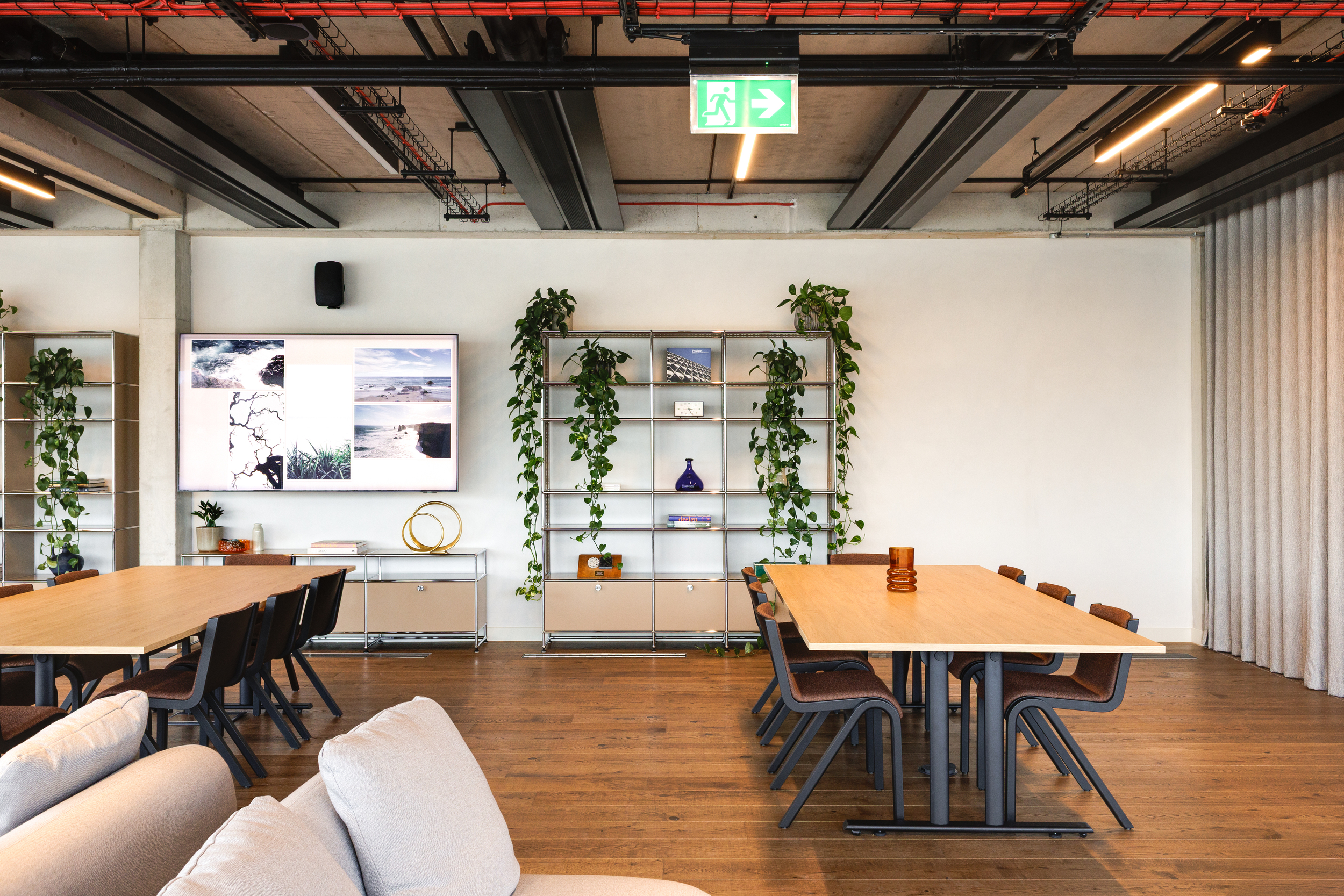 Meeting and breakout area at the Space House Clubhouse featuring timber tables, ergonomic chairs, and greenery, designed through Modus and Platfform’s modern reinterpretation of Brutalist interiors.