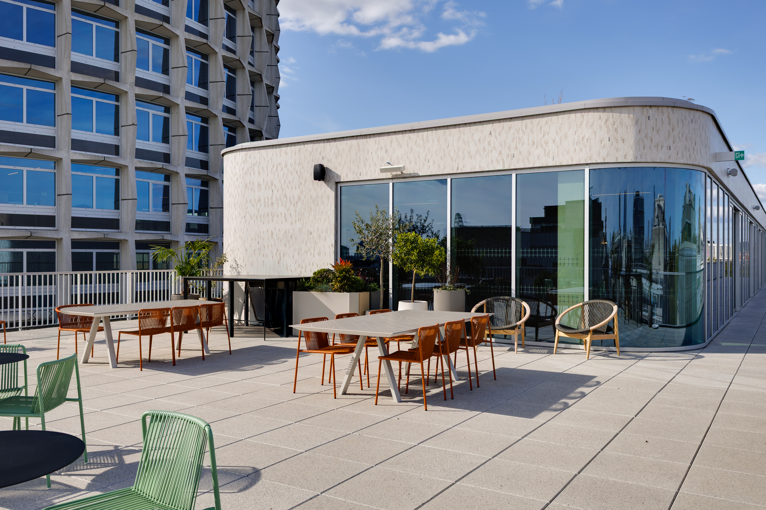 Space House Clubhouse terrace showing the curved façade and Brutalist structure alongside outdoor dining and lounge furniture from Platfform, part of Modus’s rooftop design for flexible tenant use.