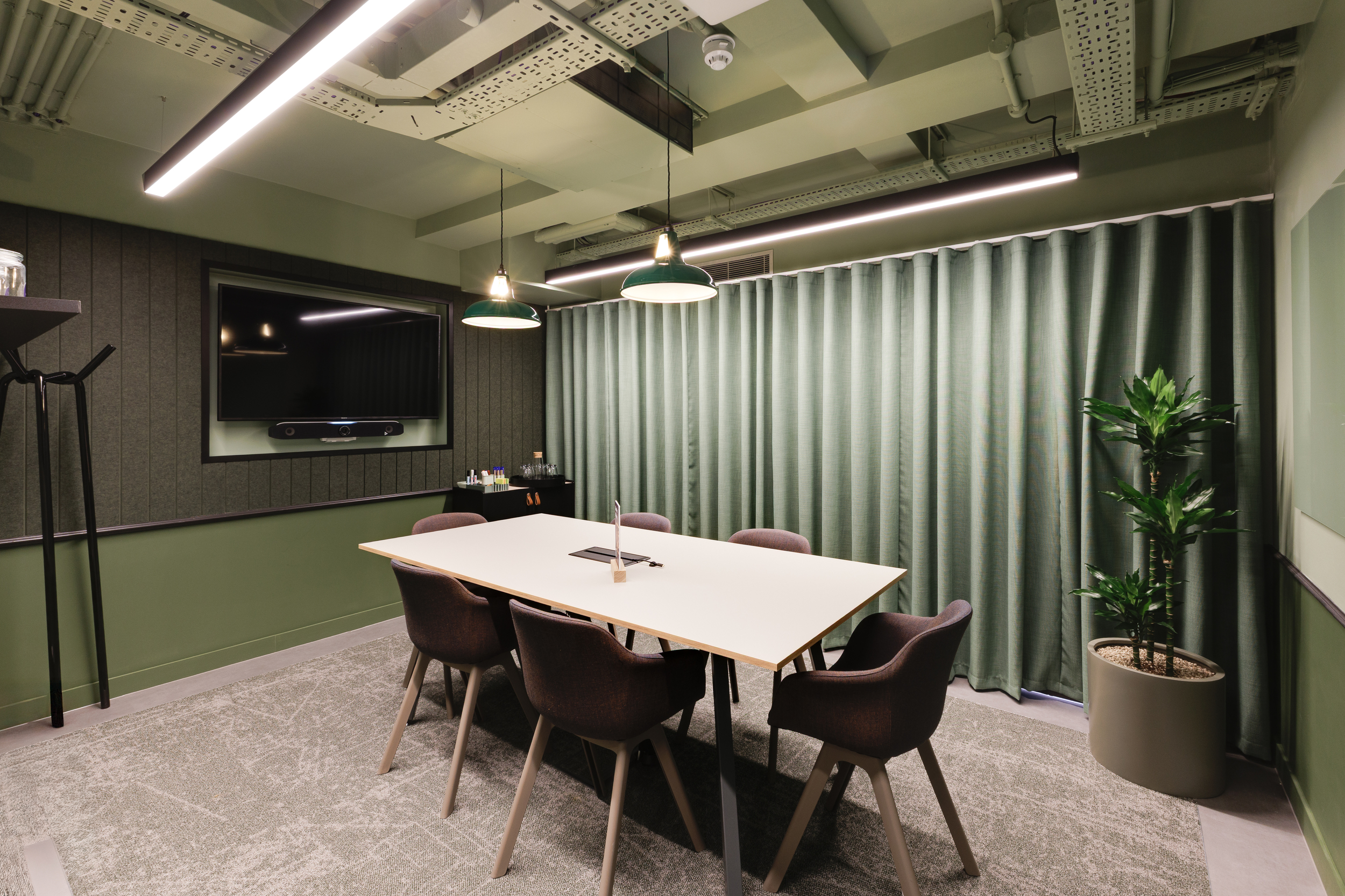 Lower ground meeting room at Work.Life Clerkenwell Green featuring green acoustic walls, matching curtains and warm lighting, furnished through Two and Platfform’s workspace collaboration.